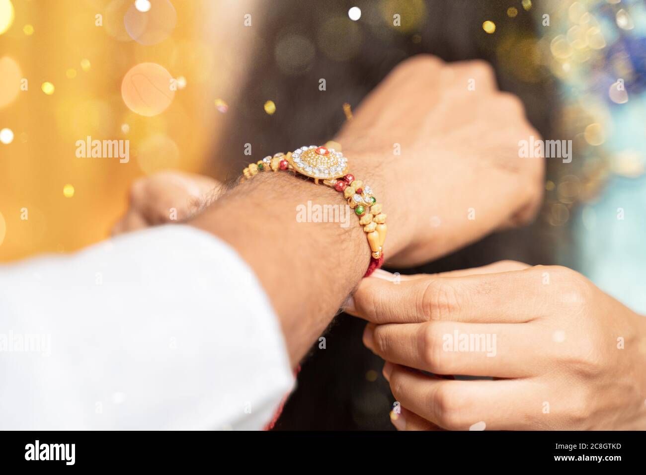 Gros plan des mains, sœur qui lie rakhi, Raksha bandhan au poignet de son frère pendant le festival ou la cérémonie - Rakshabanghan a célébré à travers l'Inde comme Banque D'Images