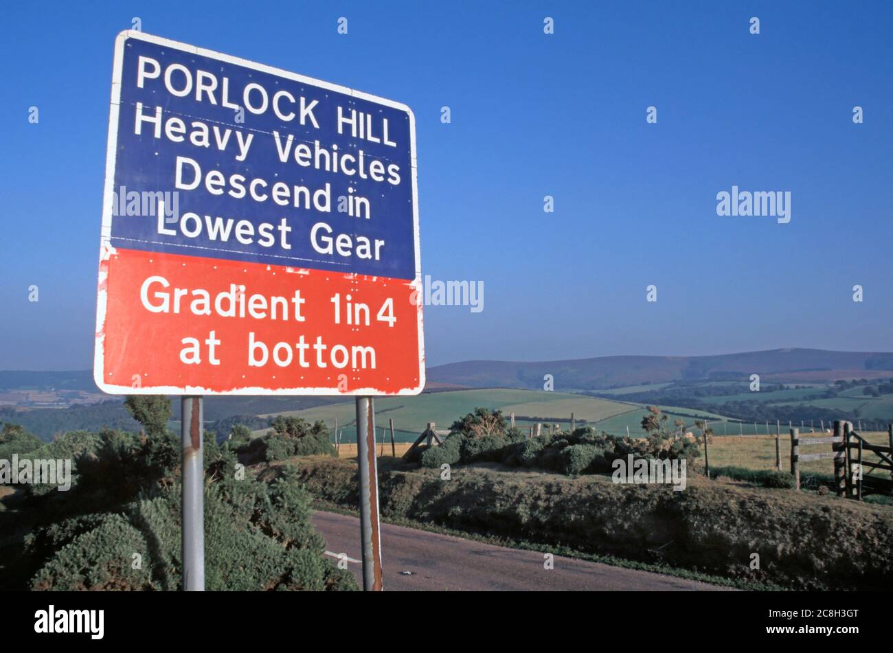 Panneau d'avertissement de la circulation routière à Porlock Hill sur la pente raide A39 indiquant l'utilisation de bas engrenage vallonné terres agricoles paysage Somerset Angleterre Royaume-Uni Banque D'Images
