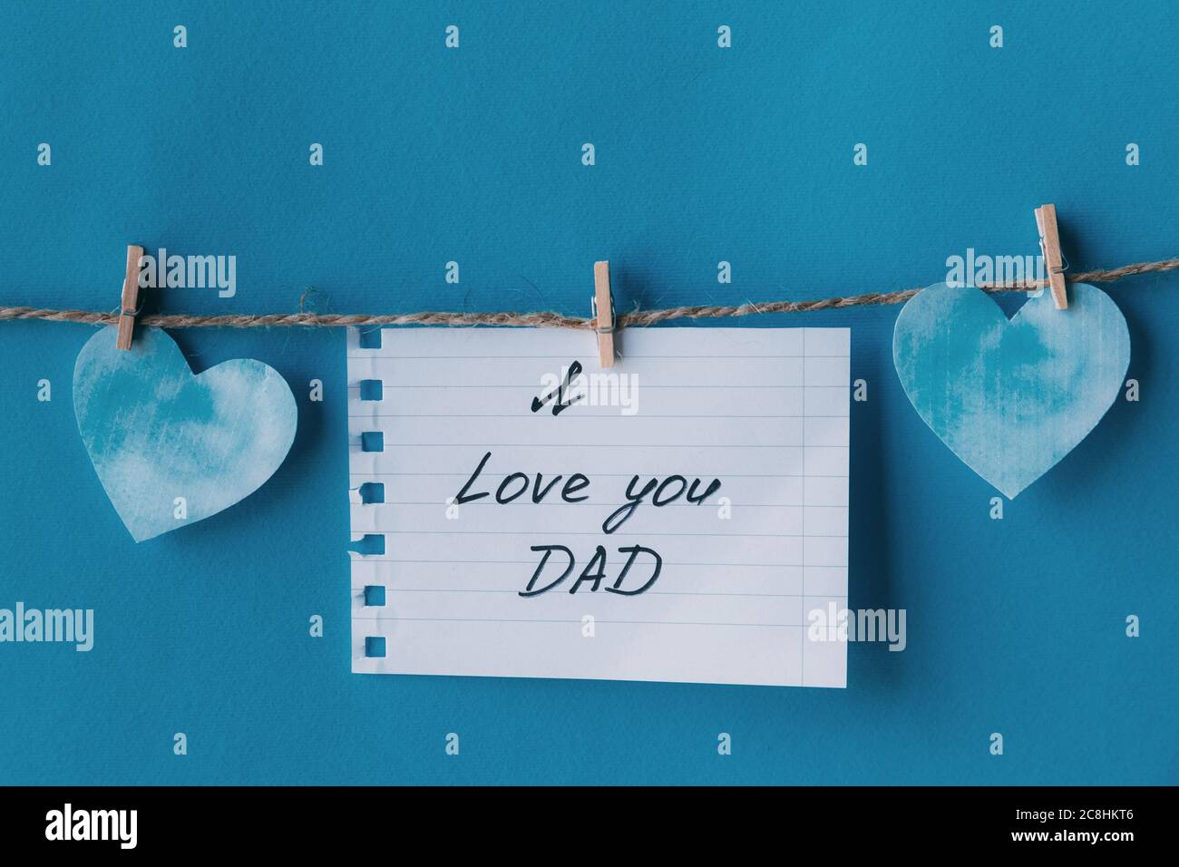 Fête des pères. Carnet blanc en ligne papier carte de voeux avec noir manuscrit lettrage je vous aime papa suspendu sur corde avec des épingles à linge isolées sur b Banque D'Images