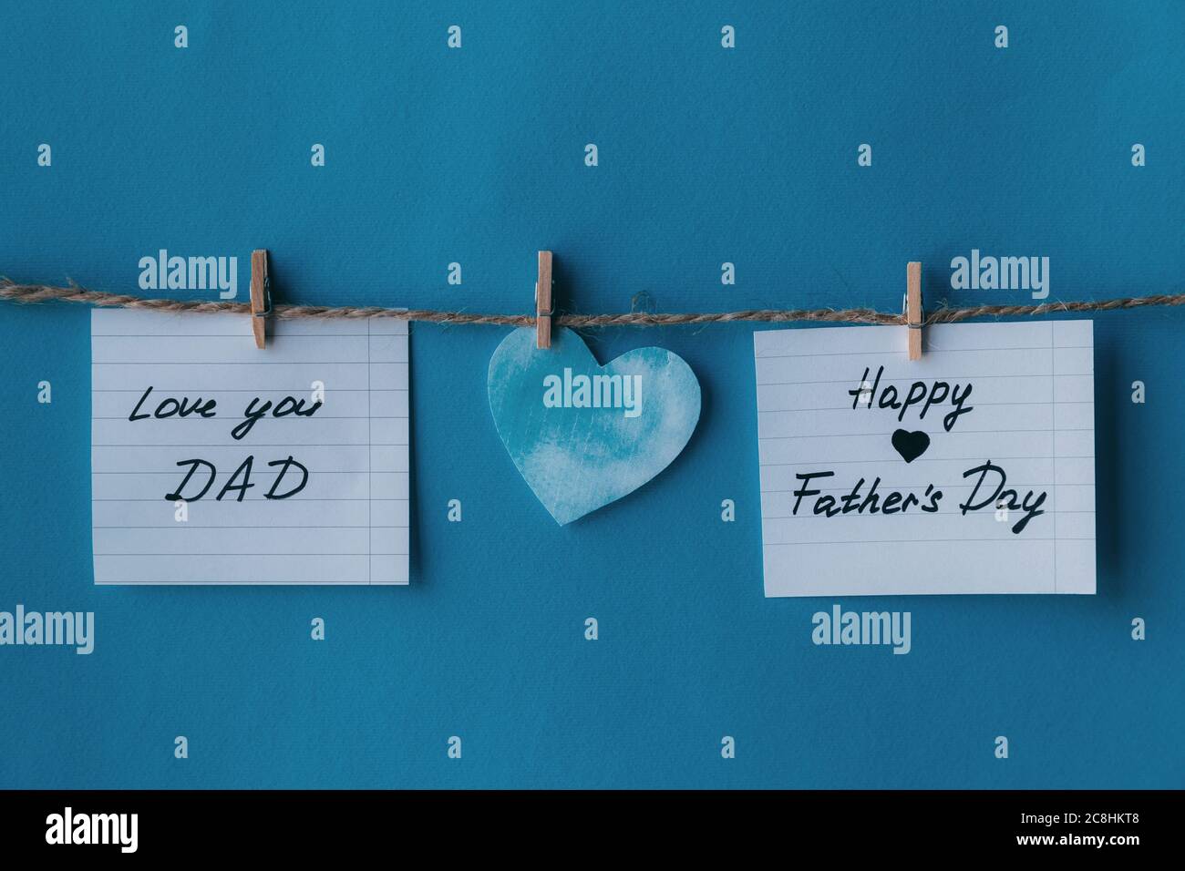 Deux carnets blancs en ligne carte de vœux en papier avec des lettres manuscrites noires Happy Pathers day et je t'aime papa suspendu sur corde marron avec le clothe Banque D'Images