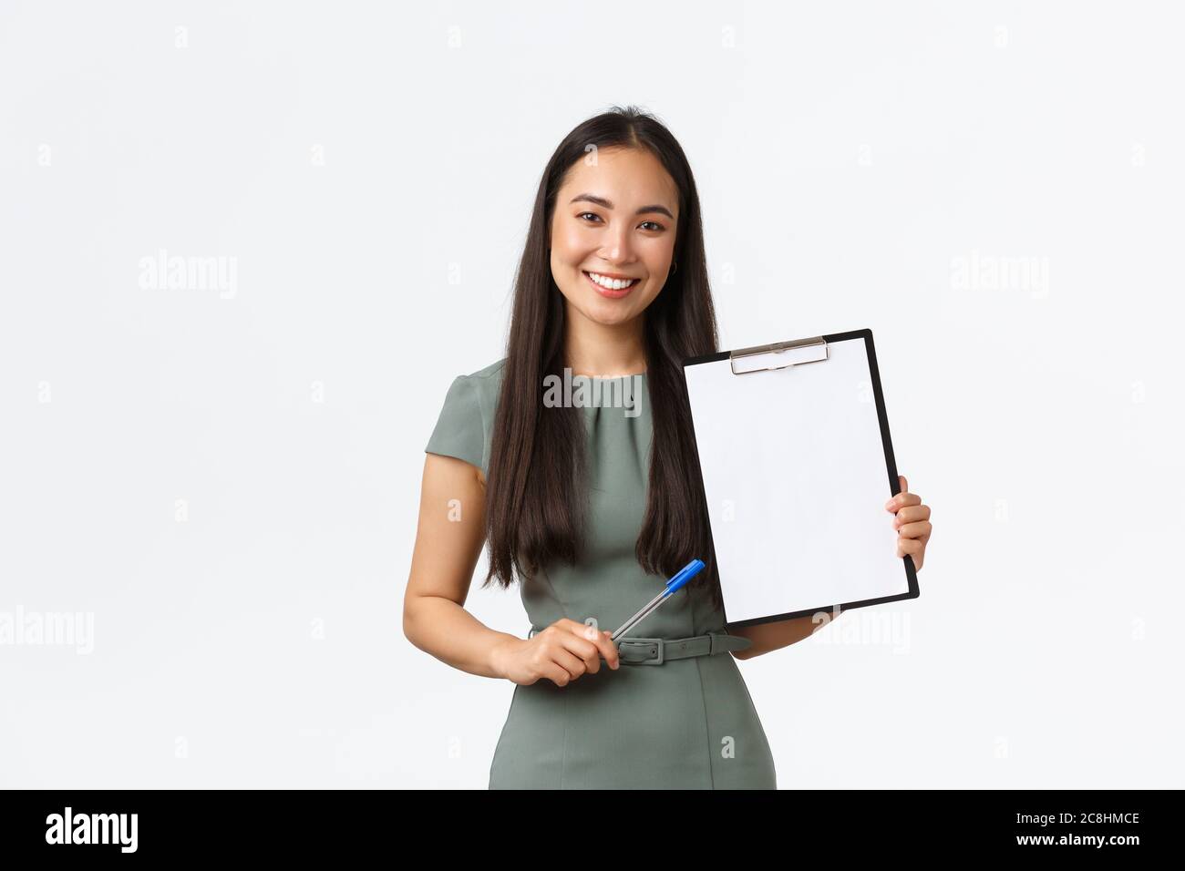 Femme d'affaires asiatique souriante montrant des papiers, un document d'avion, montrer le presse-papiers vierge et utiliser le stylo décrire les informations, debout en blanc Banque D'Images