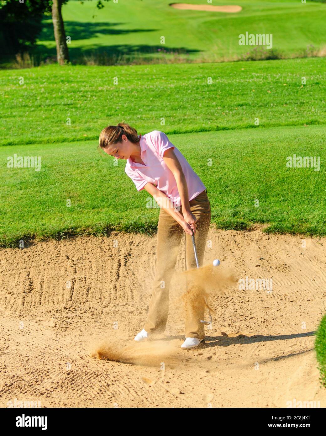 Jeune joueuse de golf jouant au ballon dans un bunker de sable Banque D'Images