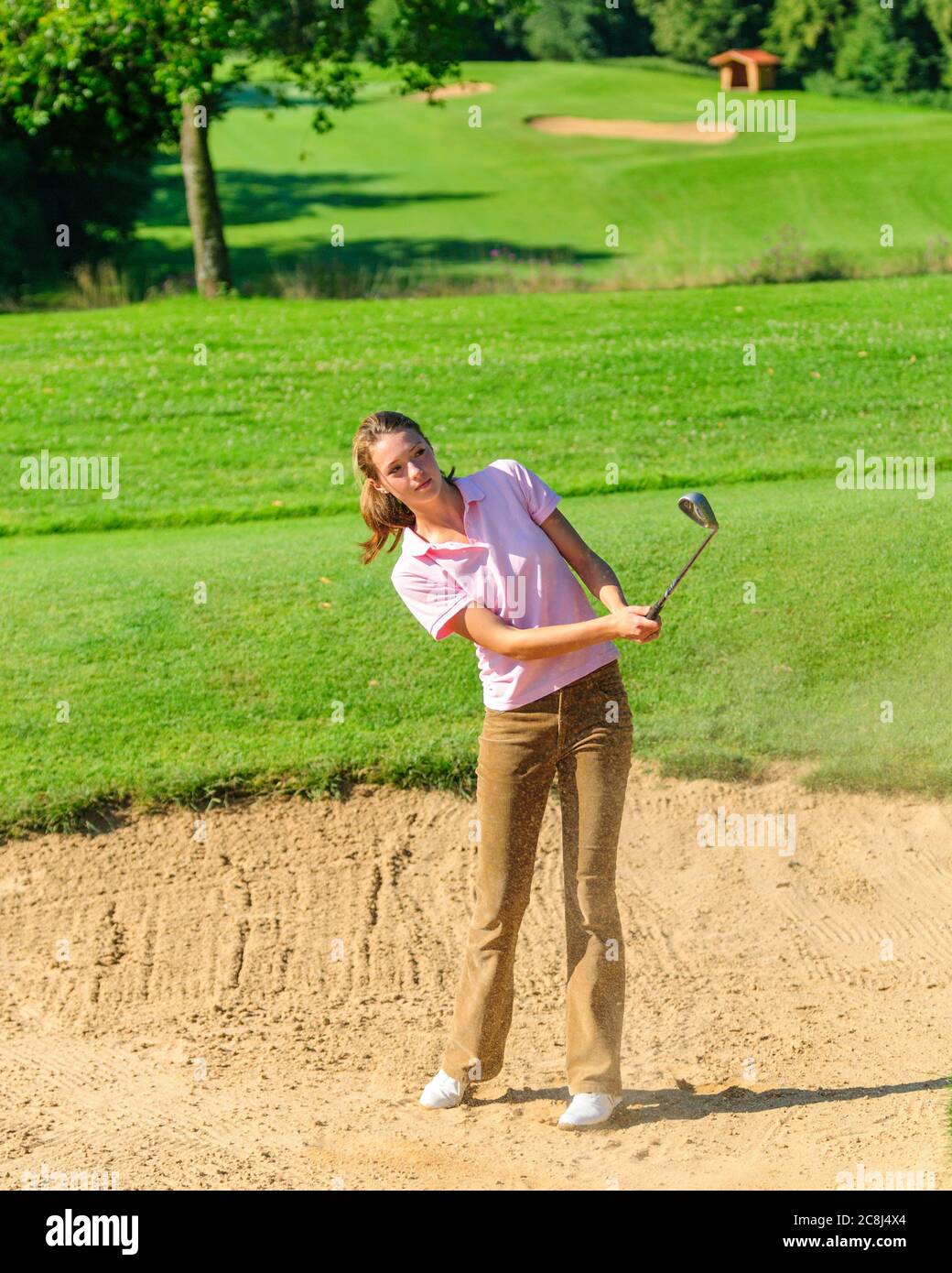 Jeune joueuse de golf jouant au ballon dans un bunker de sable Banque D'Images