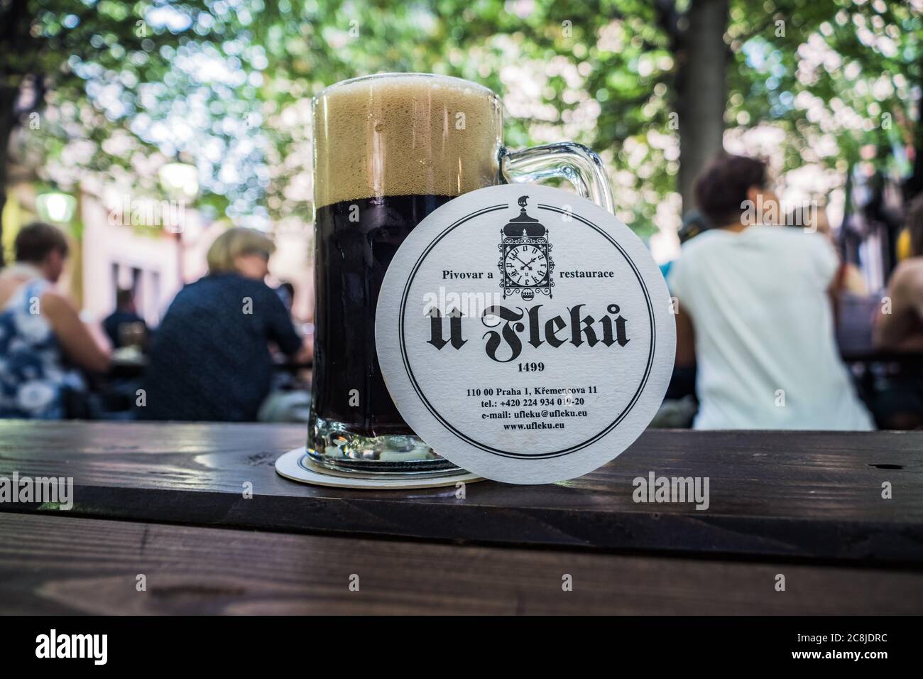 Prague, République Tchèque - juillet 10 2020 : verre avec bière foncée dans le jardin U Fleku avec dessous de verre et logo sur une table. Banque D'Images