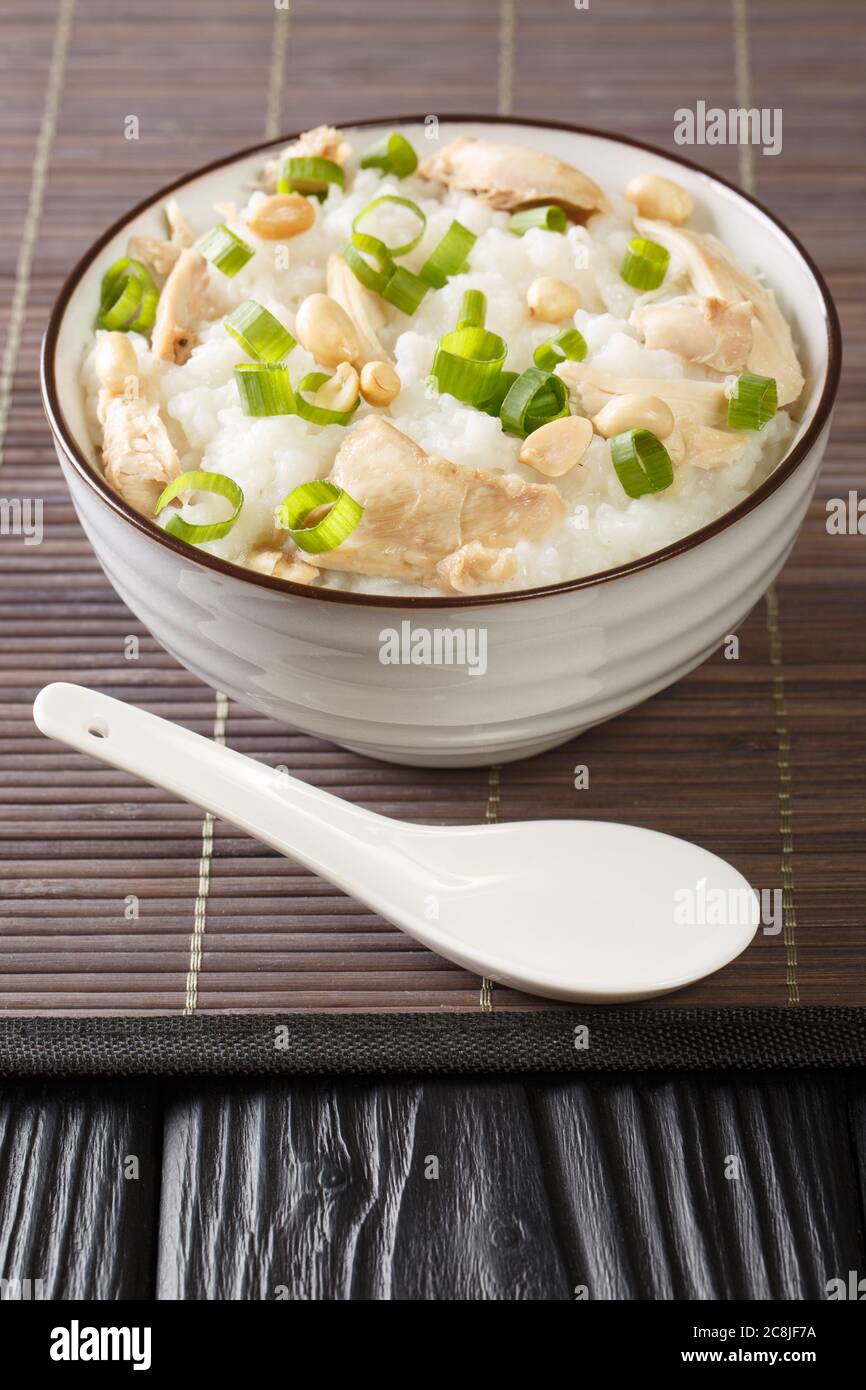 Poulet au gingembre Jook gros plan sur le porridge de riz dans un bol sur la table. Verticale Banque D'Images
