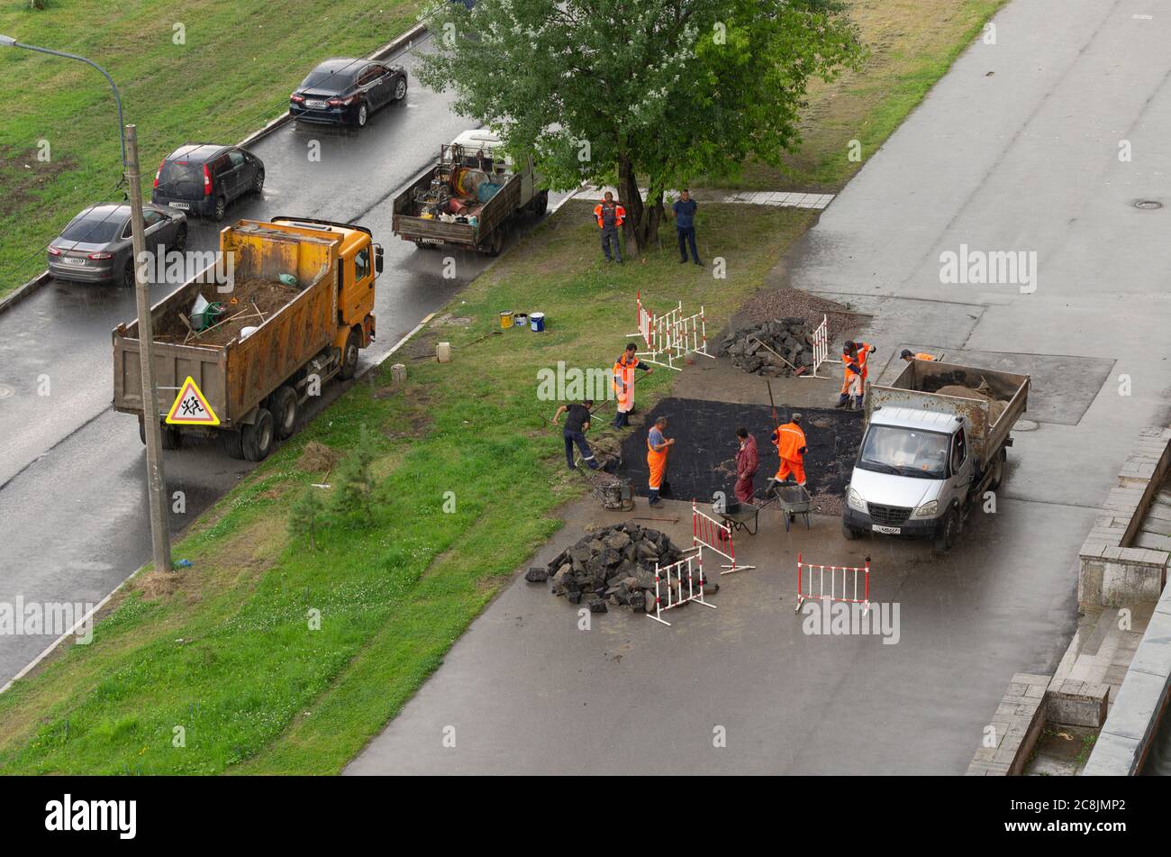 Saint-Pétersbourg, Russie - 28 juillet 2019: Ouvriers en combinaison orange qui travaillent sur la pose d'asphalte par temps pluvieux la vue du dessus Banque D'Images