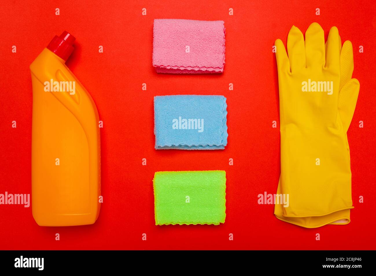 gants de toilette jaunes et chiffons sur fond rouge. CopySpace Banque D'Images