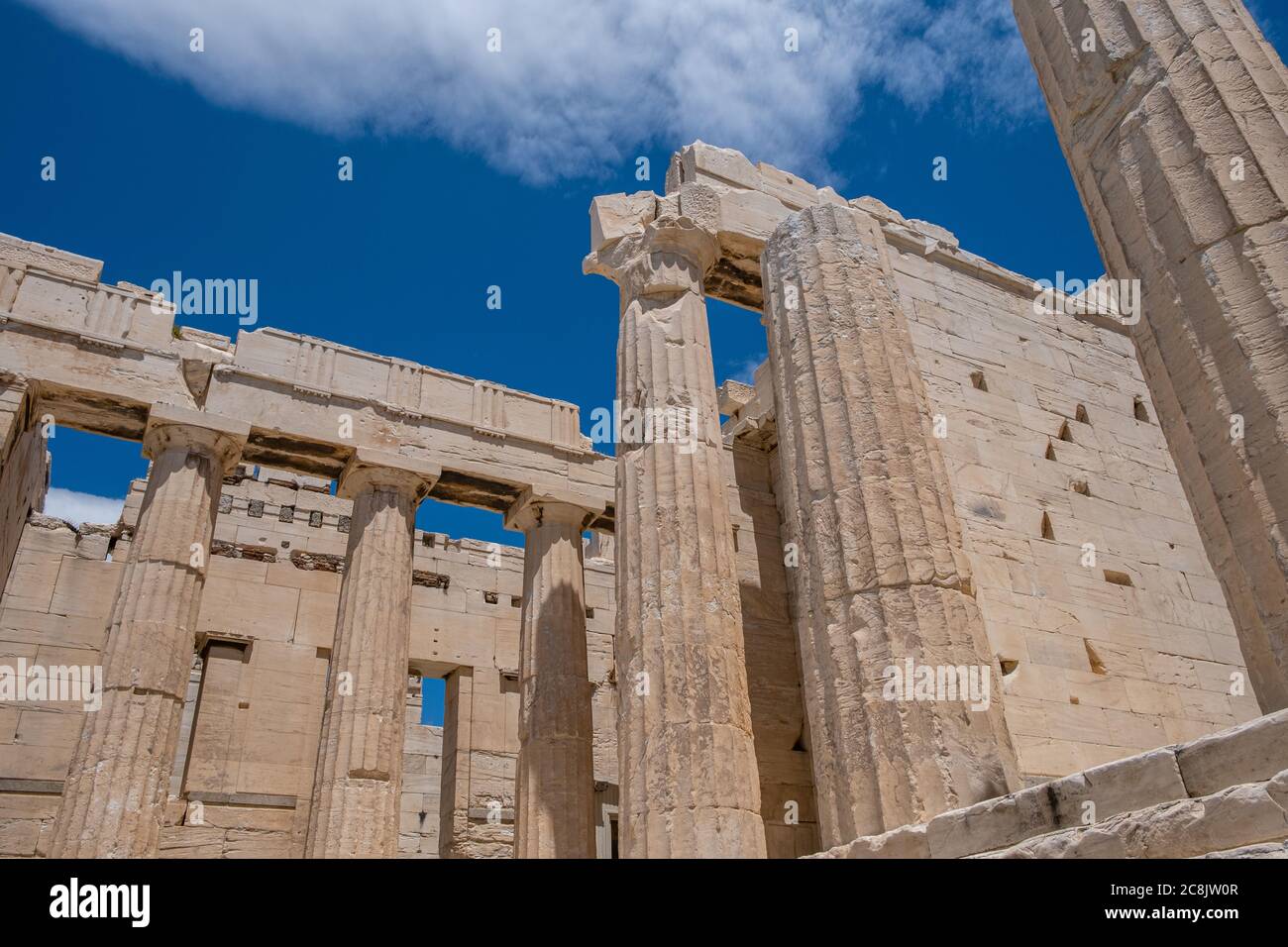 Athènes Acropole, site touristique de la Grèce. Vue à angle bas des piliers grecs anciens à la porte d'entrée de Propylaea, ciel bleu nuageux. Banque D'Images