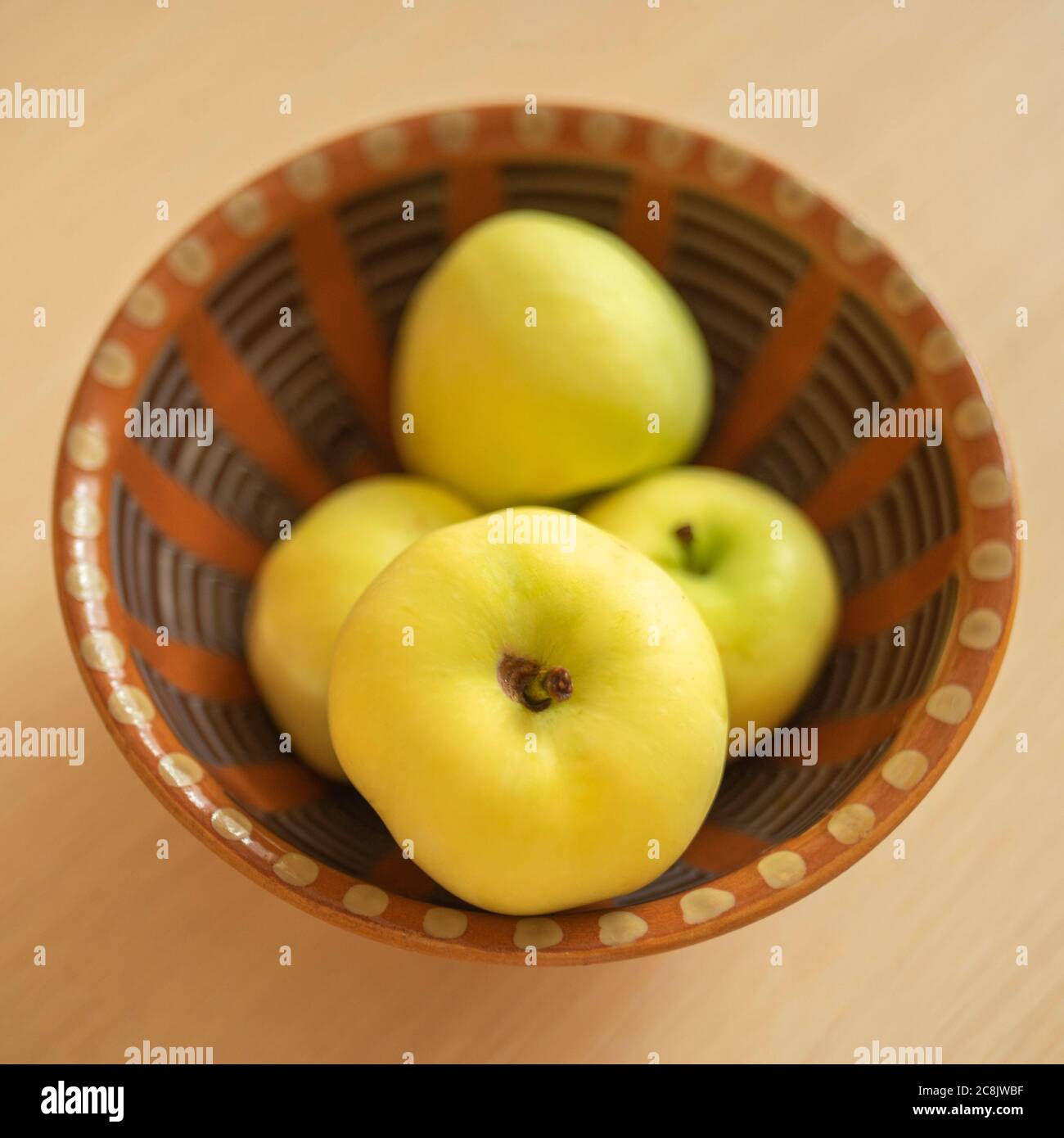 Pommes vertes mûres dans un bol en argile brune. Banque D'Images