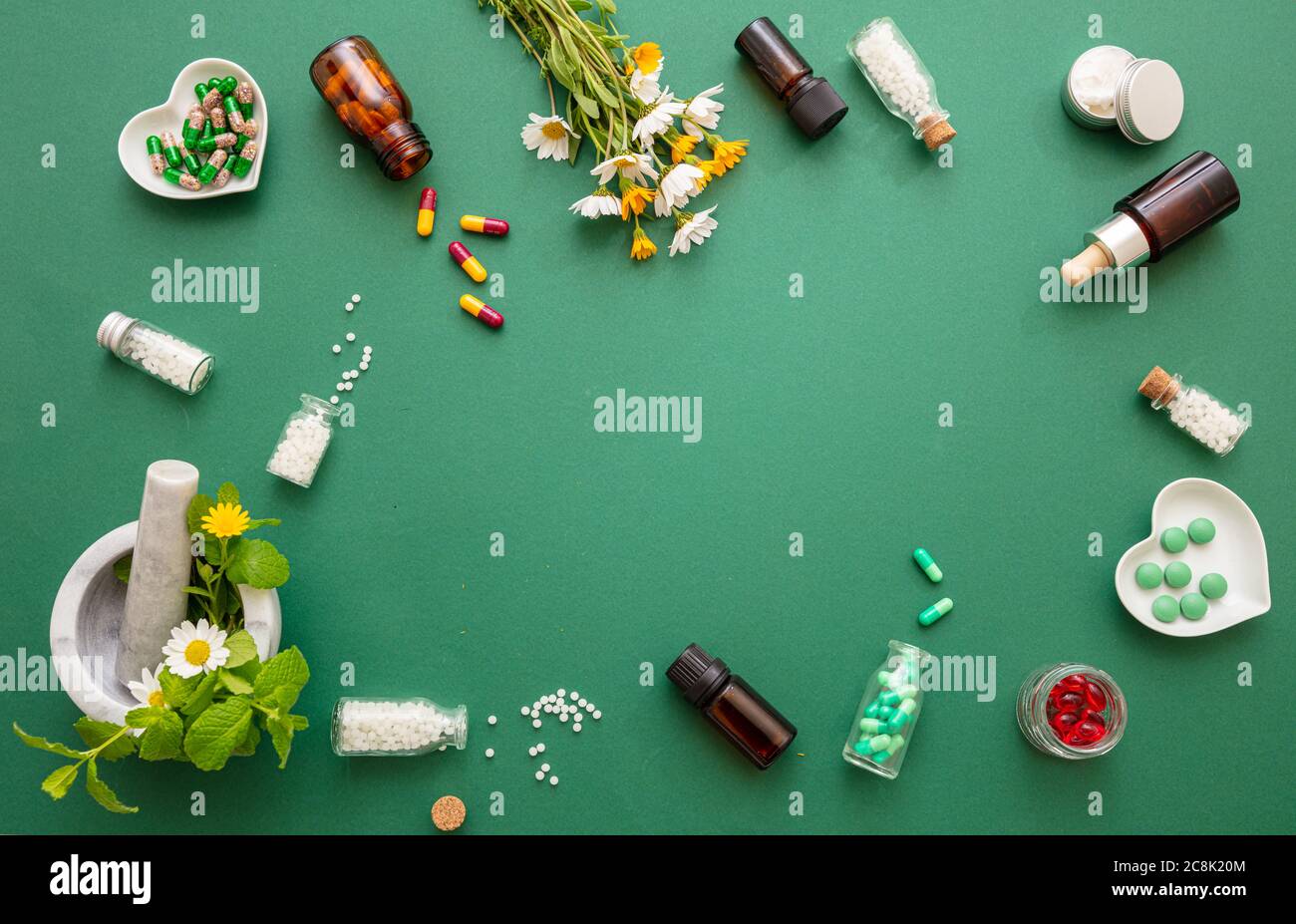 Médecine alternative à base de plantes. Les globules homéopathiques, les fleurs sauvages fraîches et les herbes plates sont sur fond vert. Aromathérapie, homéopathie produit naturel Banque D'Images
