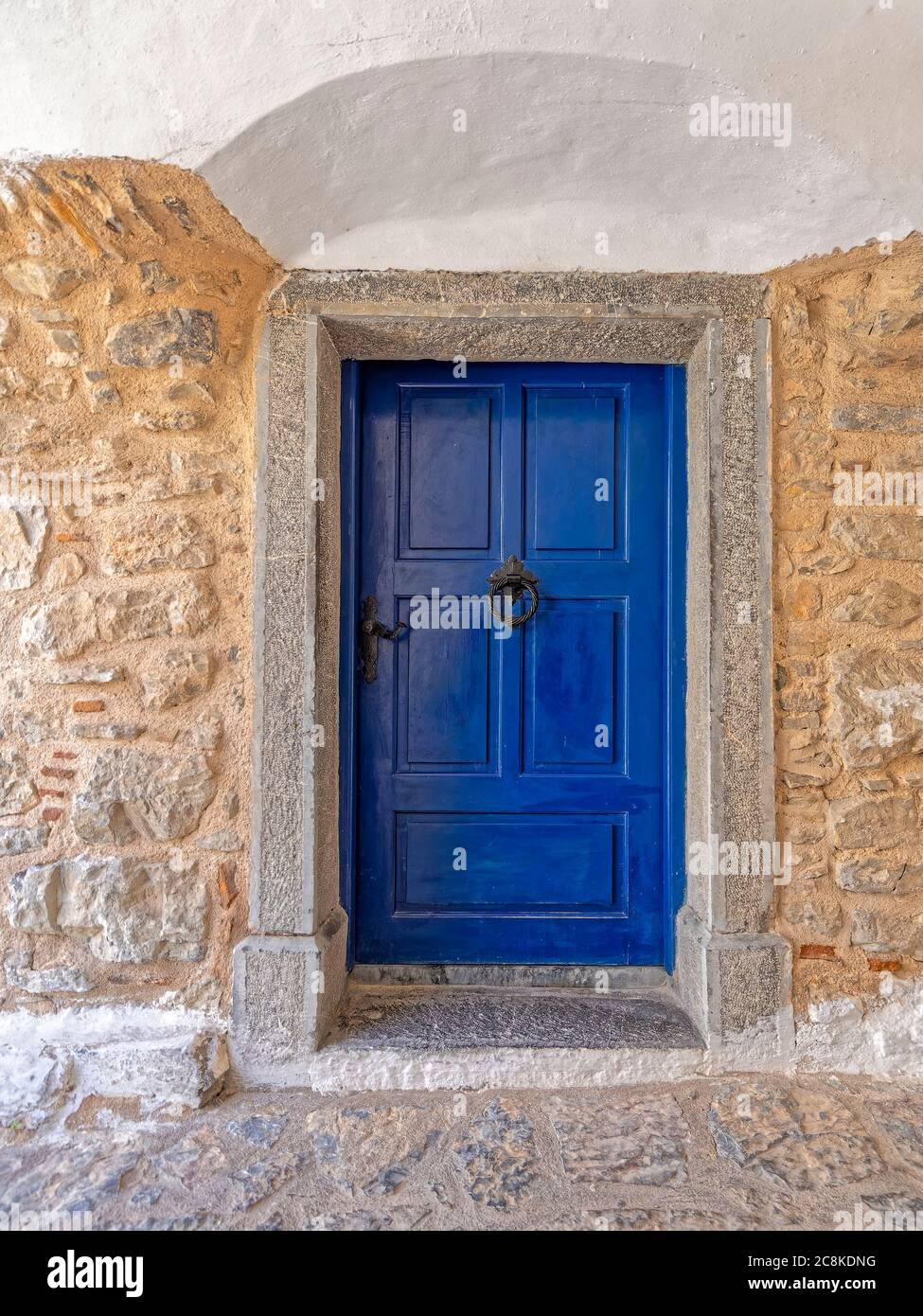 Porte bleu vif en pierre rugueuse et façade de maison blanchie à la chaux. Promenade dans les ruelles médiévales de Pyrgi, île de Chios, Grèce. Banque D'Images