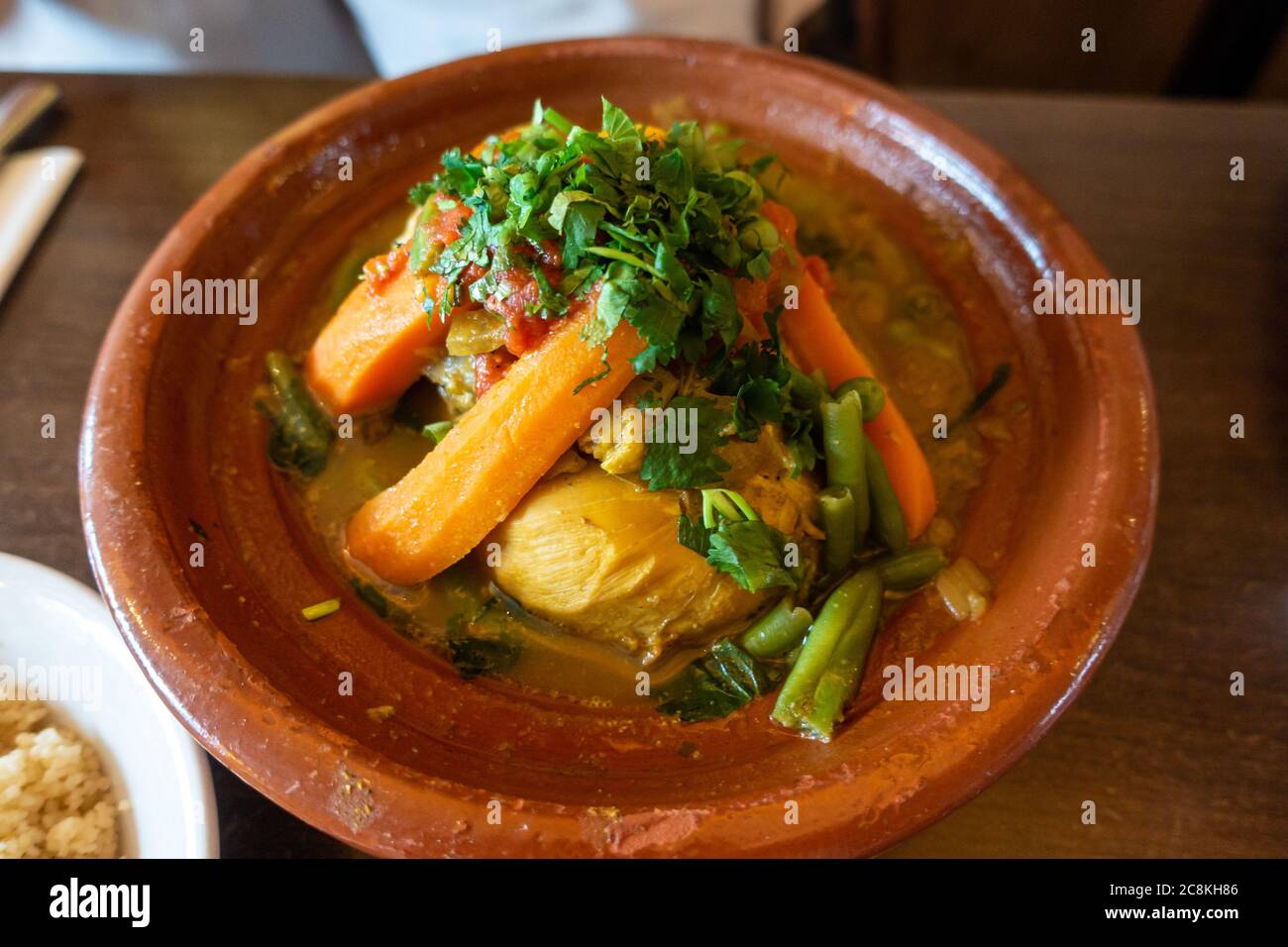 Tagine de poulet, plat marocain, avec légumes servis sur un lieu de poterie rustique. Banque D'Images
