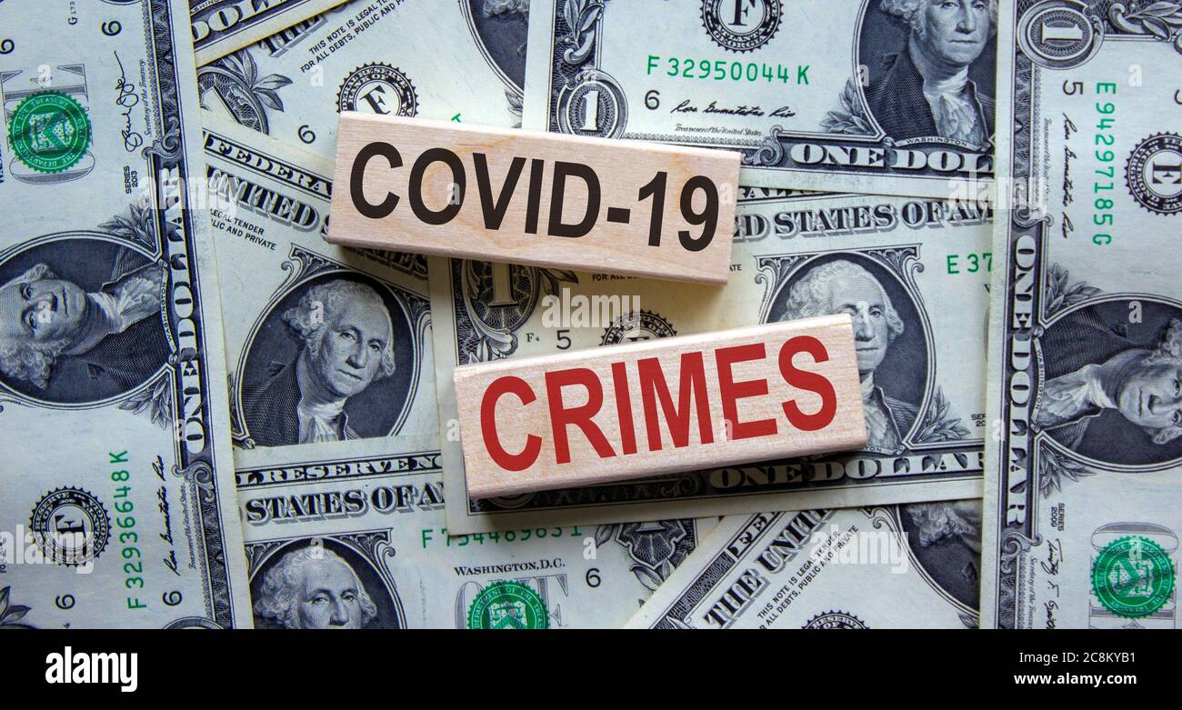 Mots « Covid-19 crimes » sur des blocs de bois. Concept d'entreprise. Magnifique arrière-plan de billets de dollars. Banque D'Images