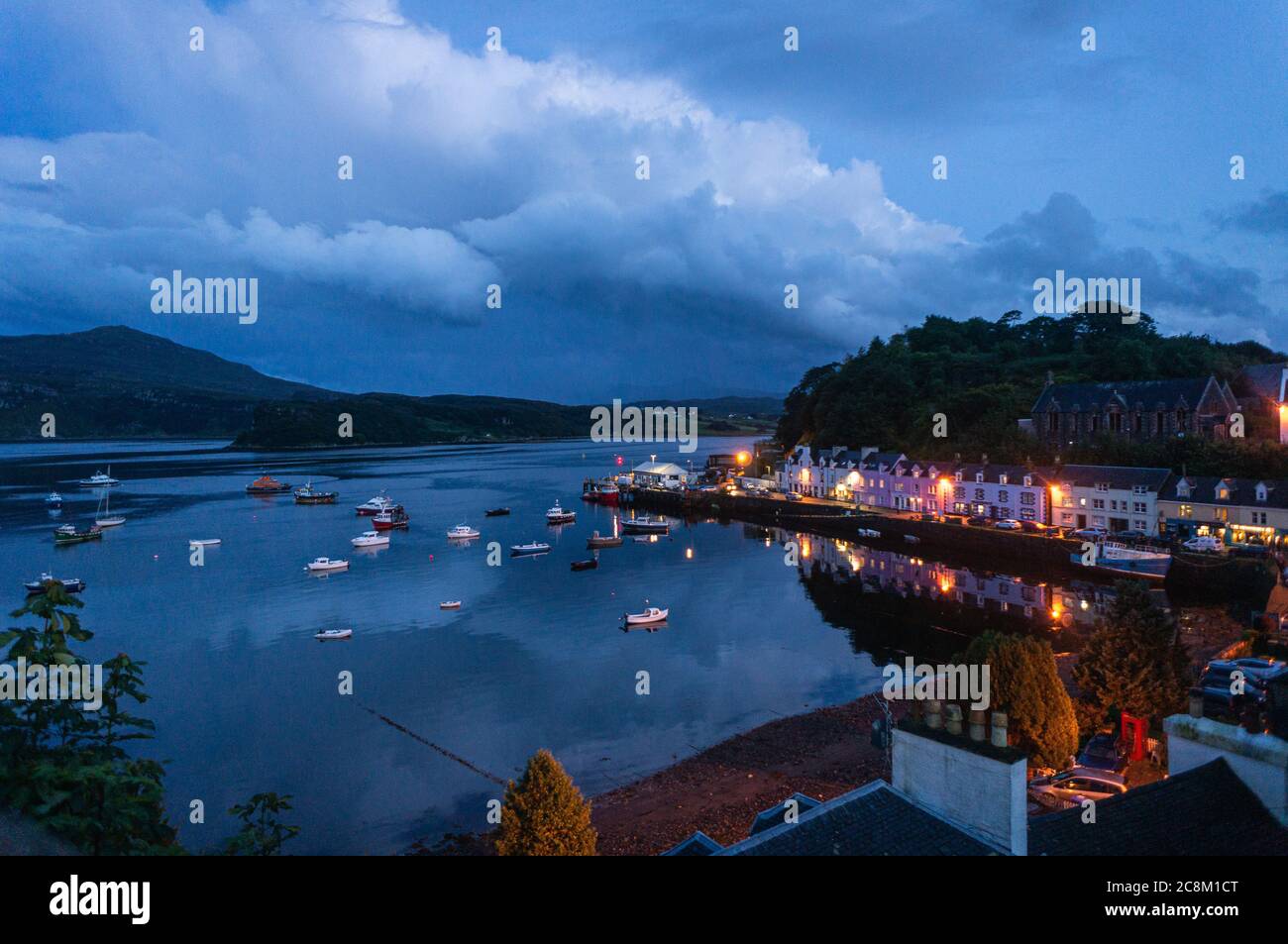 Belle petite ville portuaire la nuit, le port de Portree la nuit, à l'île de Skye. Petits bateaux de pêche et réflexions sur l'eau. Banque D'Images