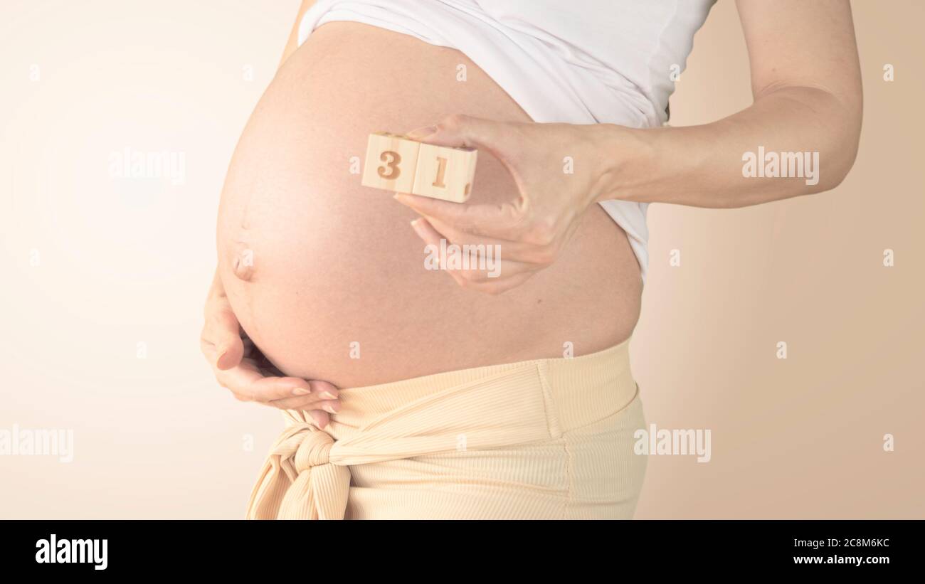 Jeune femme enceinte avec numéro de semaine de grossesse à côté de son ventre. Photos de la croissance du ventre à 31 semaines de grossesse. Alimentation saine pendant la grossesse Banque D'Images