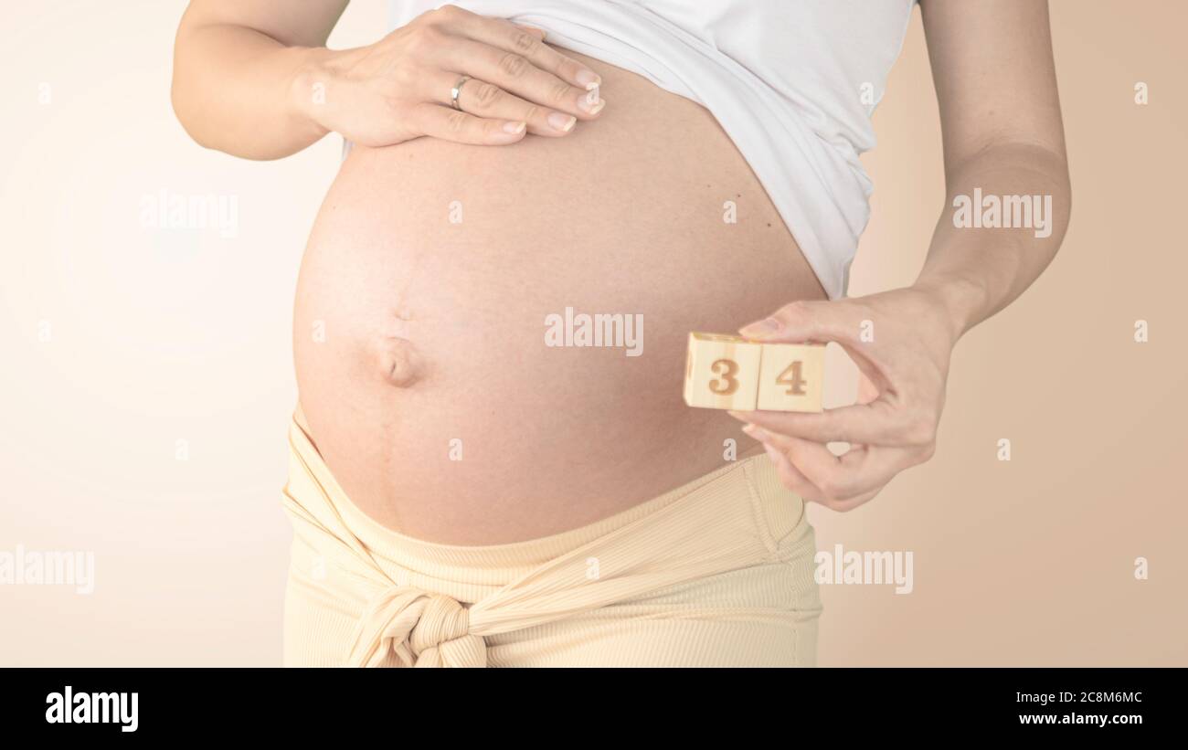 Jeune femme enceinte avec numéro de semaine de grossesse à côté de son ventre. Photos de la croissance du ventre à 34 semaines de grossesse. Alimentation saine pendant la grossesse Banque D'Images