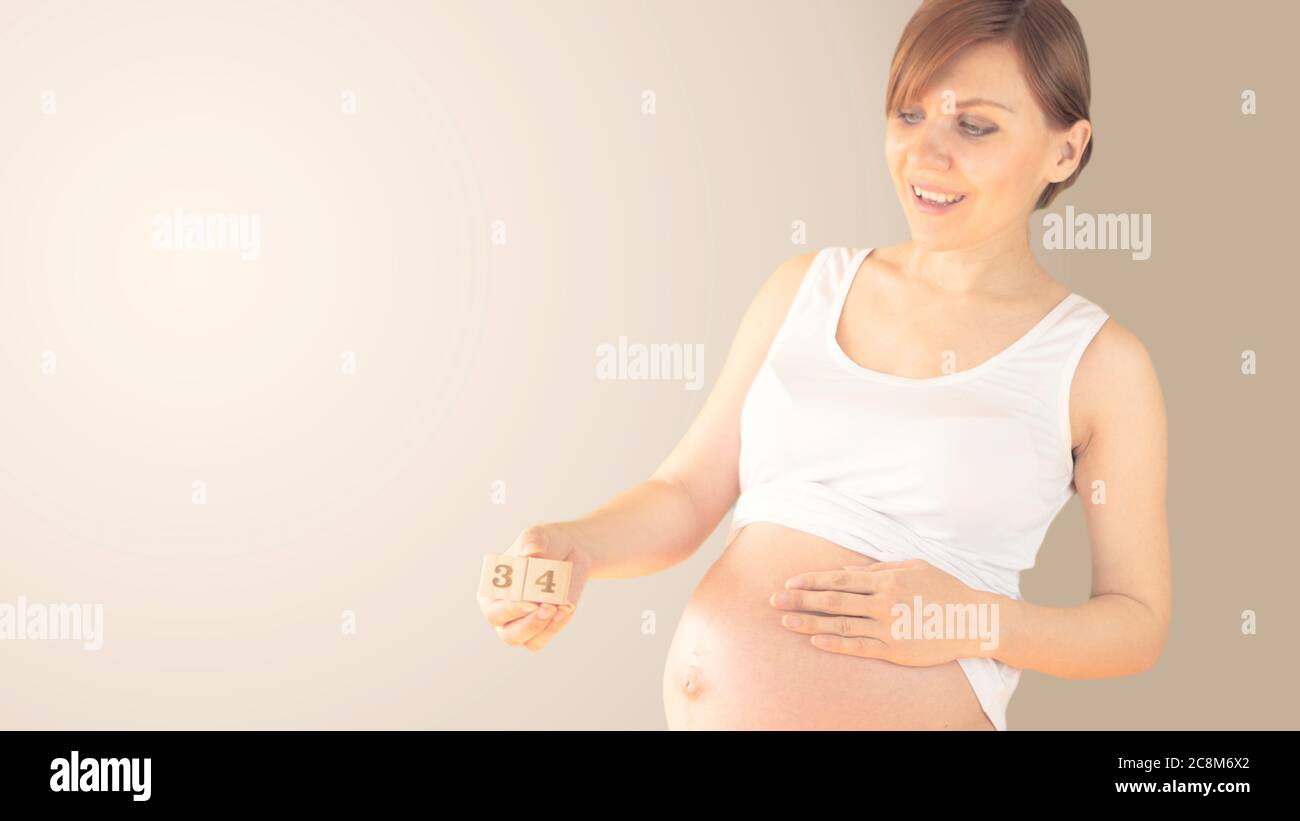 Jeune femme enceinte avec numéro de semaine de grossesse à côté de son ventre. Photos de la croissance du ventre à 34 semaines de grossesse. Alimentation saine pendant la grossesse Banque D'Images