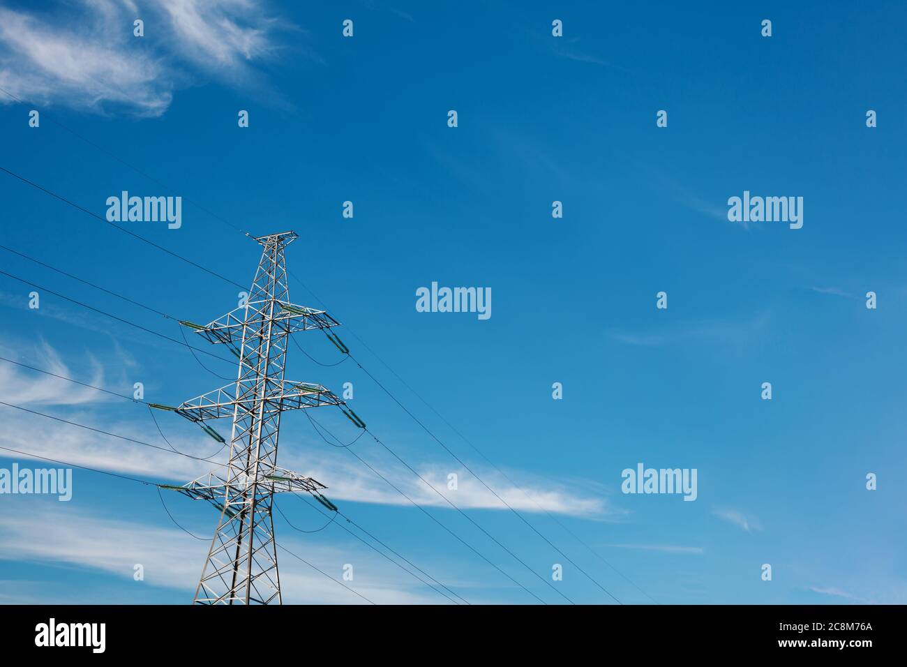 Tour haute tension contre ciel bleu avec nuages blancs. Ligne de transmission électrique avec espace de copie Banque D'Images