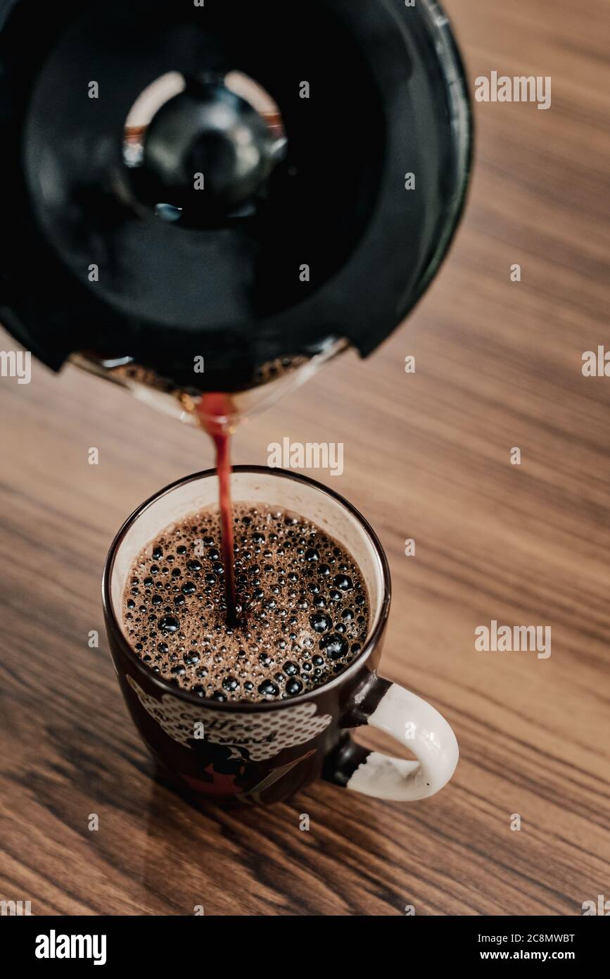 Un homme verse du café noir dans une tasse Banque D'Images