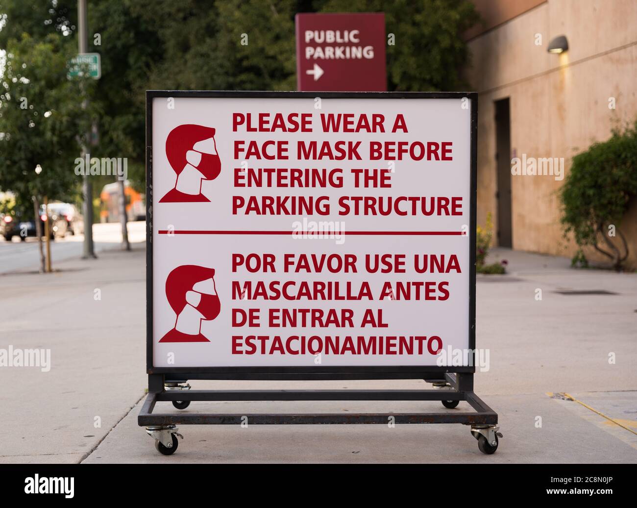 Panneau indiquant « Veuillez porter un masque avant d'entrer dans la structure de stationnement » devant un garage public dans le centre-ville de Los Angeles, en Californie. Banque D'Images
