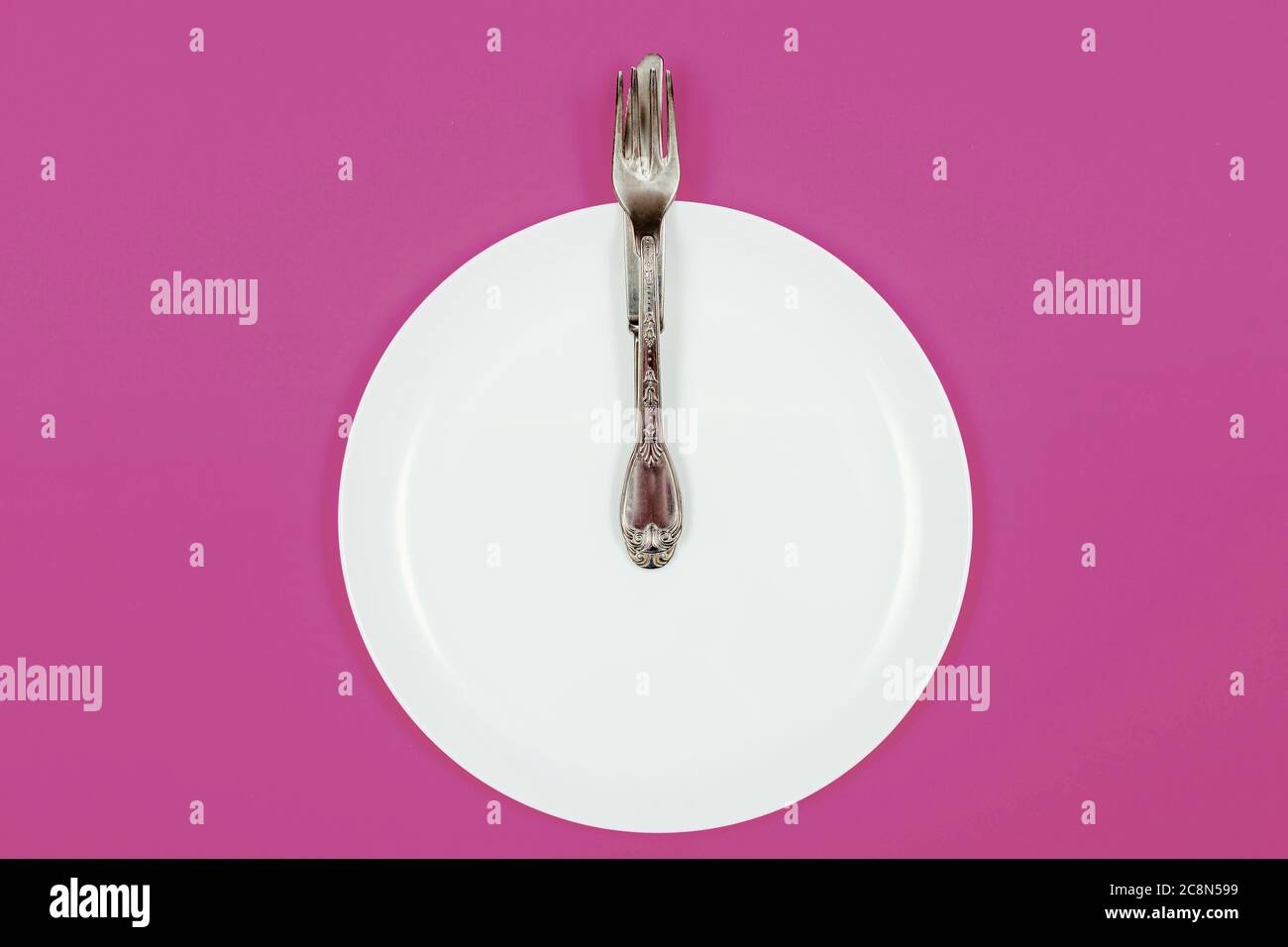 Heure du repas de nuit, assiette comme une horloge montre minuit sur fond violet Banque D'Images