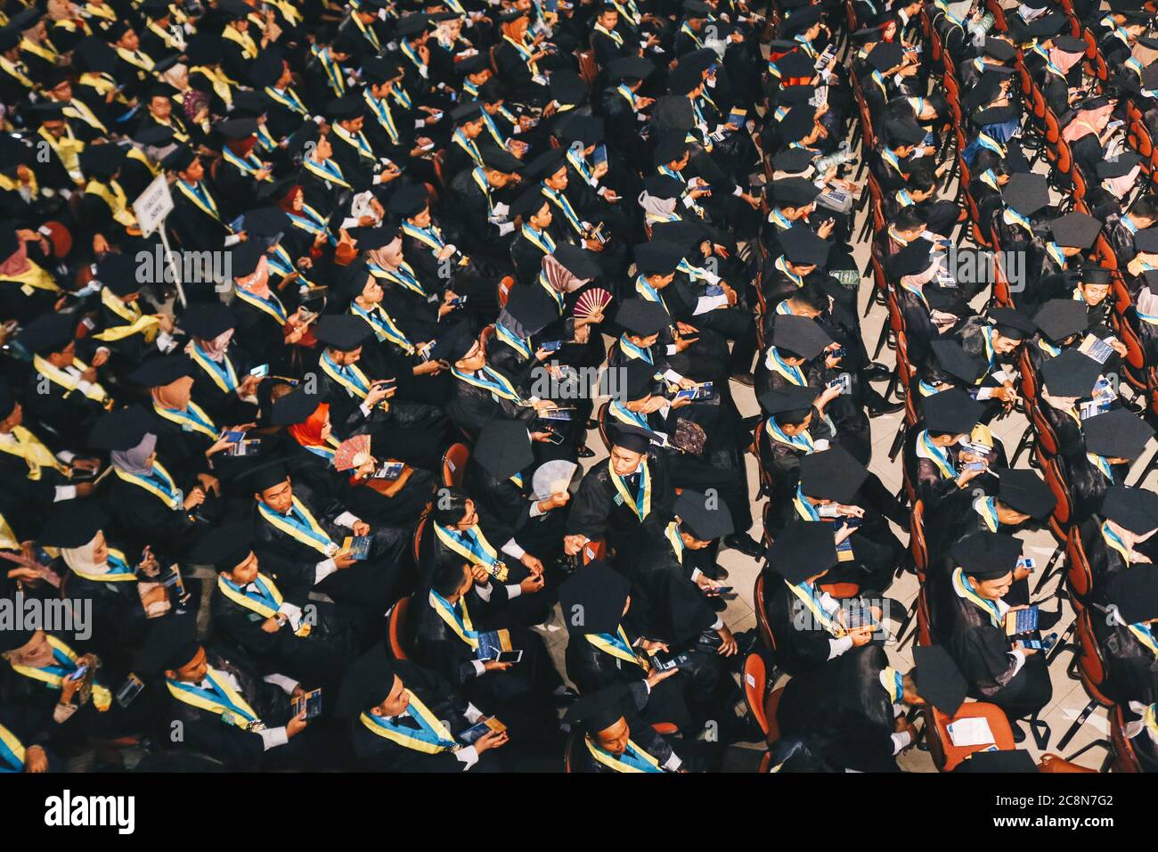 Vue de dessus du groupe de diplômés universitaires en robes noires s'aligne pour le diplôme de la cérémonie de remise des diplômes universitaires. Yogyakarta, Indonésie - décembre 2019. Banque D'Images