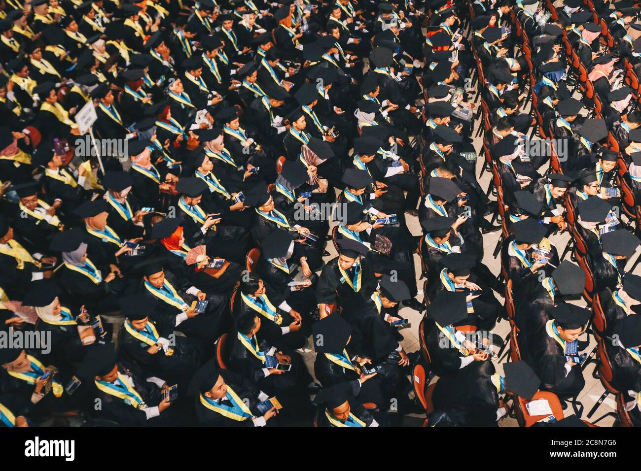 Vue de dessus du groupe de diplômés universitaires en robes noires s'aligne pour le diplôme de la cérémonie de remise des diplômes universitaires. Yogyakarta, Indonésie - décembre 2019. Banque D'Images