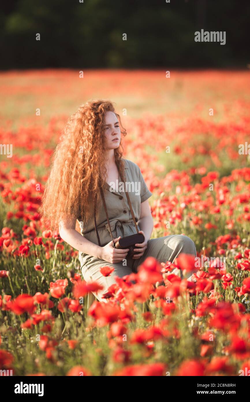 Jeune belle fille rouge-entendre prend des photos dans le champ de fleurs de pavot rouge Banque D'Images