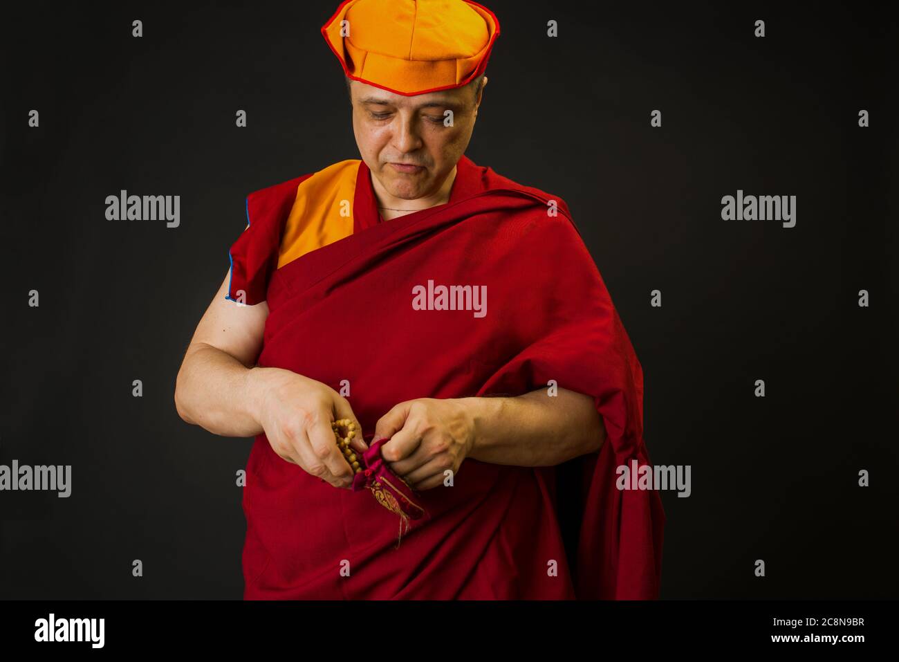 porter d'un moine bouddhiste dans une robe de lama. Le moine possède les attributs rituels du bouddhisme, du rosaire, du vajra, de la cloche Banque D'Images