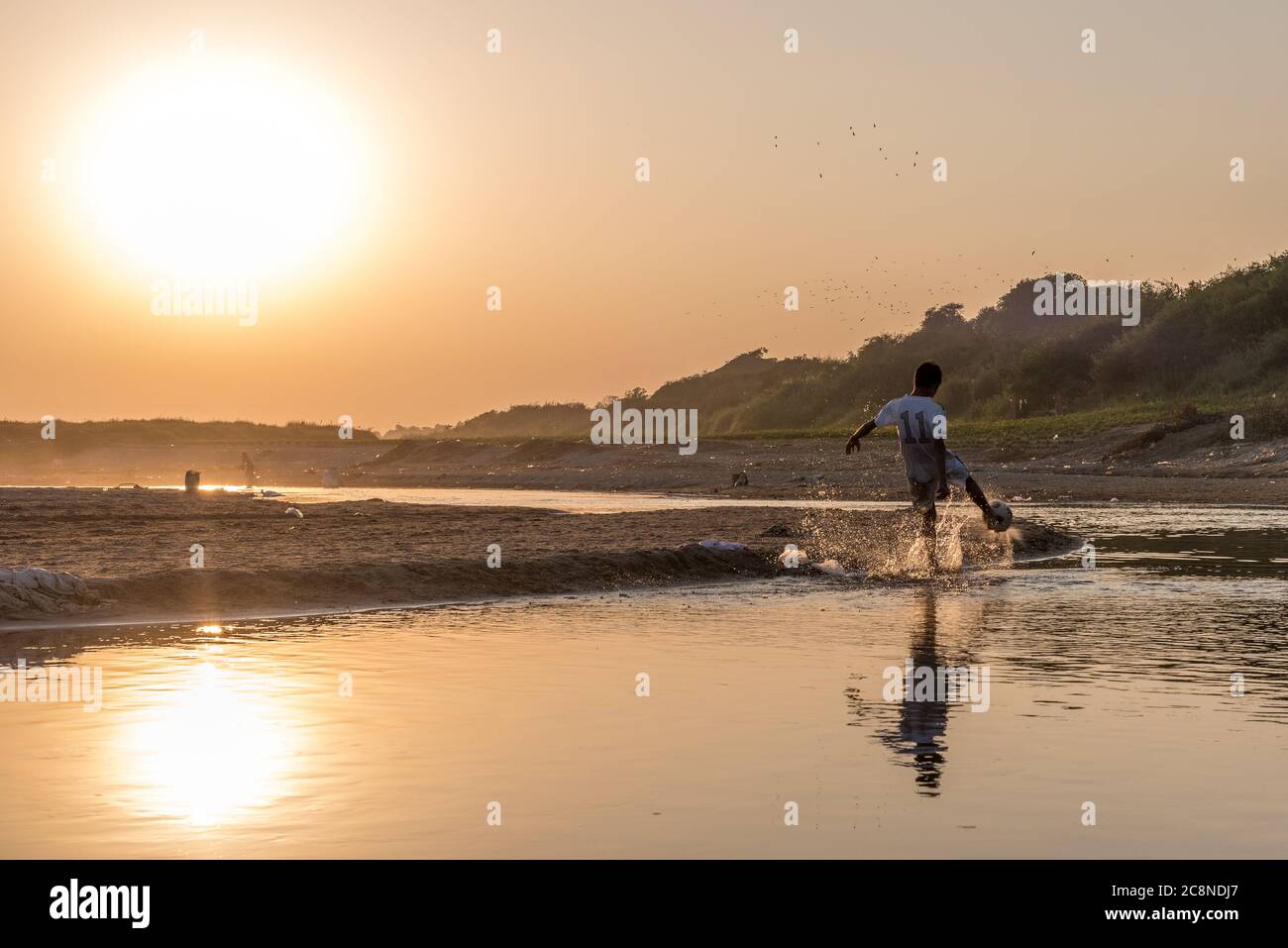 Garçons birmans jouant au football sur la rivière Irrawaddy à Pakokku, Myanmar Banque D'Images