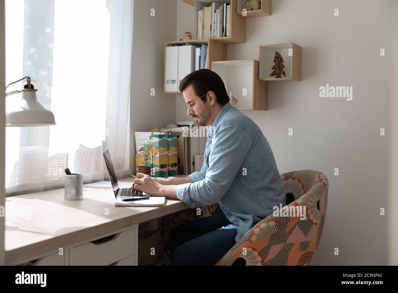Homme caucasien concentré sur le travail sur ordinateur portable à la maison Banque D'Images