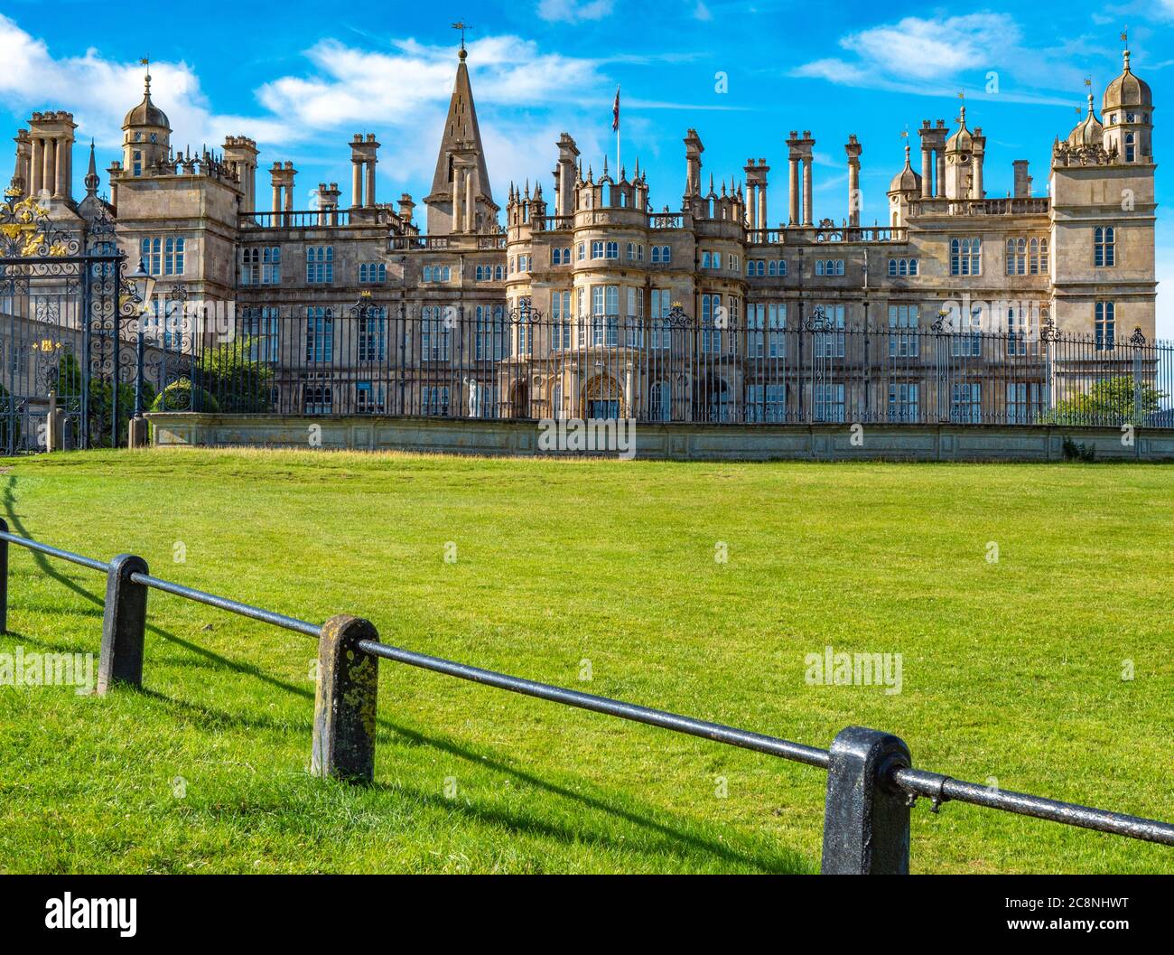 Devant la maison historique de Burghley, sous le soleil du matin, avec des rampes autour de l'herbe en premier plan. Stamford, Lincolnshire, Angleterre, Royaume-Uni. Banque D'Images