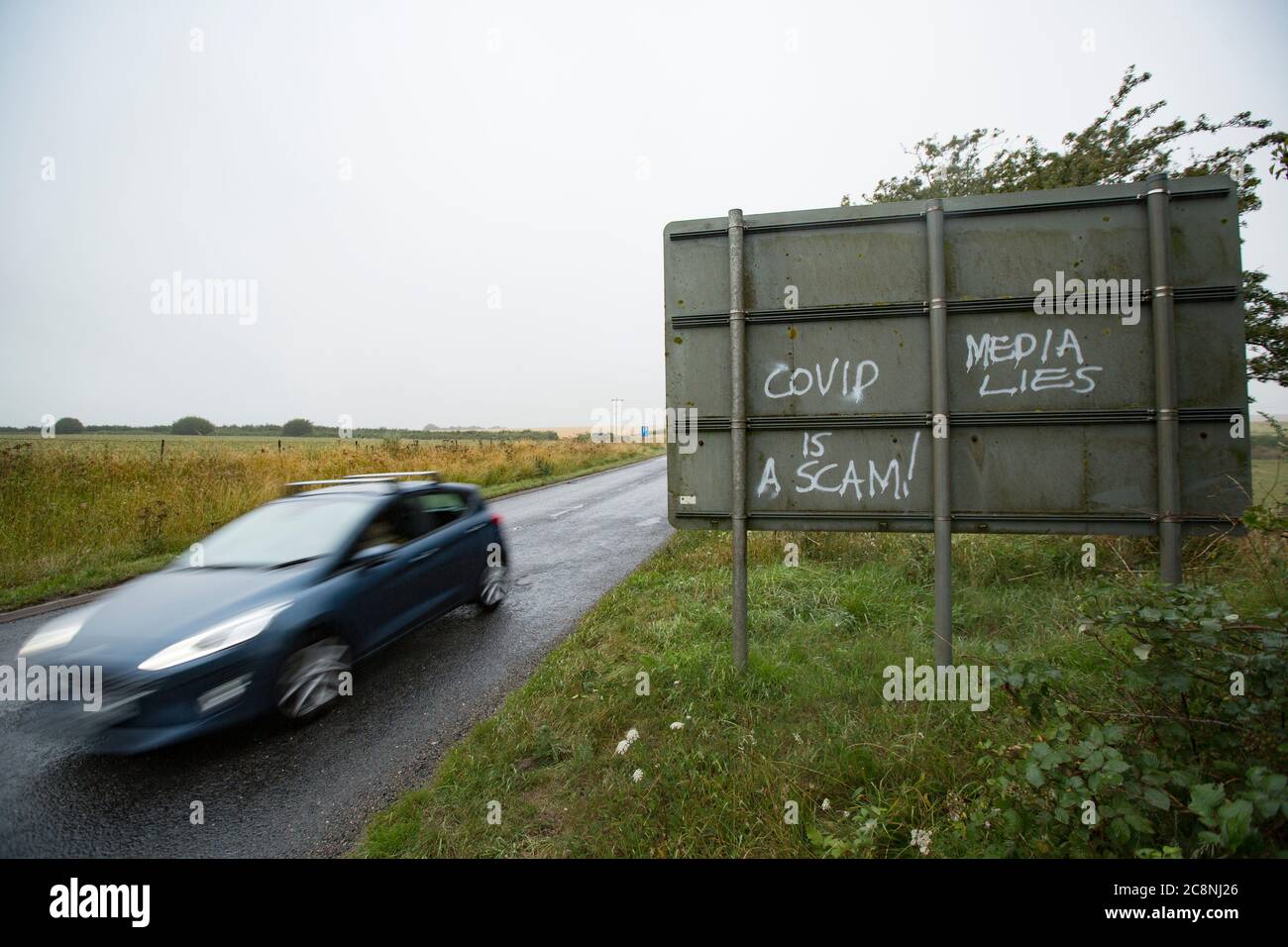 Graffiti pulvérisé sur un panneau de route dans Dorset exprimant l'opinion que le coronavirus est une arnaque et que les médias mentent. Dorset Angleterre GB Banque D'Images