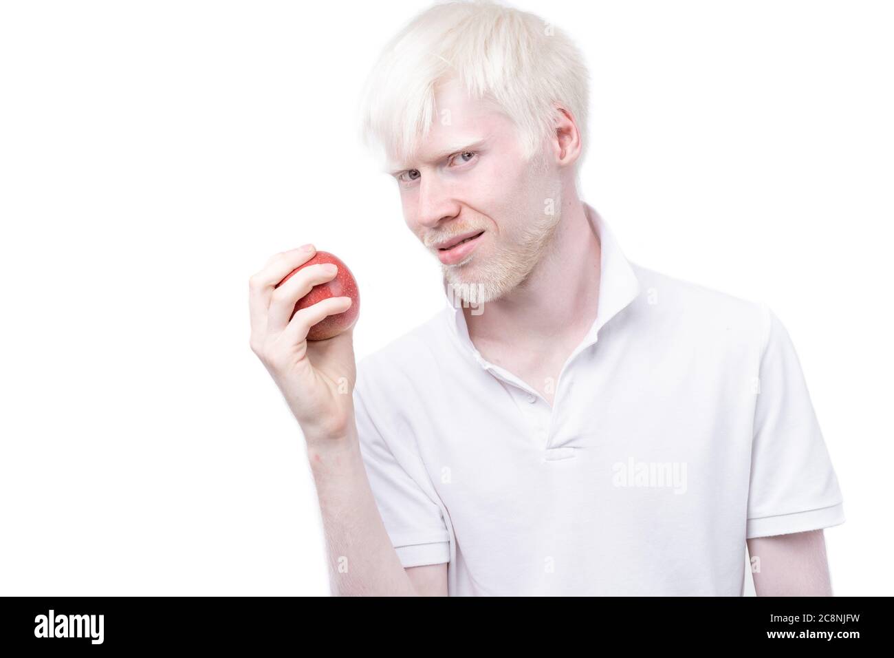 Albinisme albino homme peau blanche cheveux studio habillé t-shirt isolé fond blanc. Anomalies. Aspect inhabituel. Peau anormale belles personnes avec aspect spécial. Mangez de la pomme rouge Banque D'Images