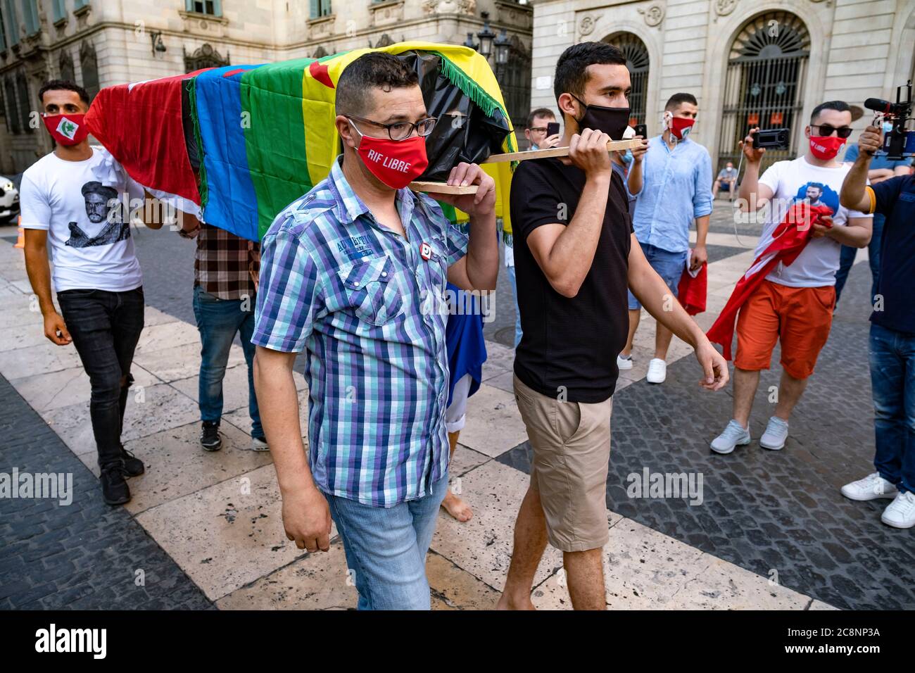 Barcelone, Espagne. 25 juillet 2020. Les partisans du mouvement populaire de RIF (Hirak) portant des masques sont vus portant un fenetro simulé couvert de drapeaux du peuple amazigh et de la République de RIF pendant le rallye.les sympathisants du mouvement populaire de RIF (Hirak) résidant en Catalogne se sont rassemblés sur la Plaza Sant Jaume à Barcelone pour commémorer la proclamation De la première république de Rif et se souvenir de leurs prisonniers politiques. Crédit : SOPA Images Limited/Alamy Live News Banque D'Images