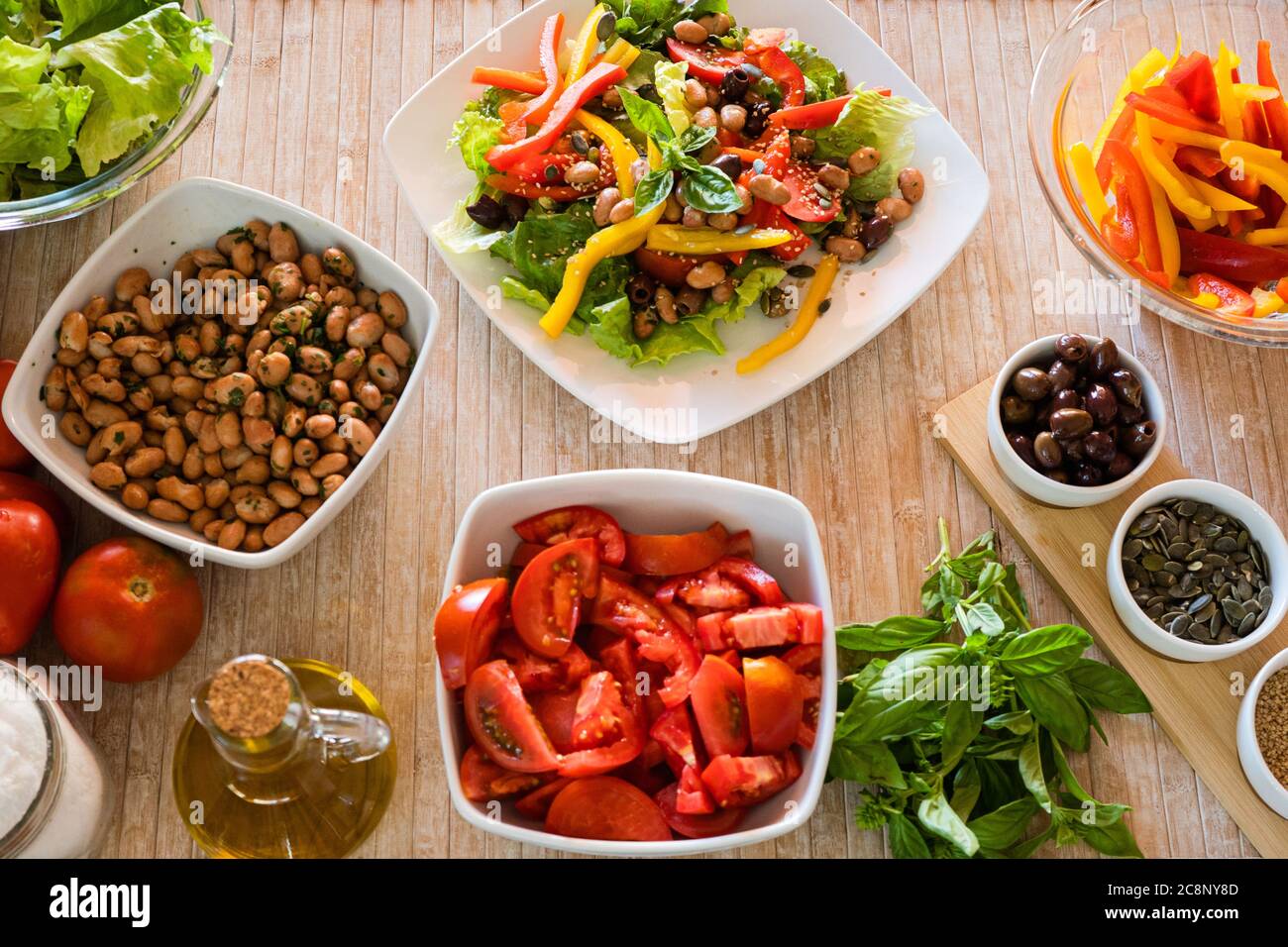 Plat Laissez le dessus d'une assiette à salade composée fraîche avec des ingrédients de légumes tout autour sur une table en bois clair et la lumière naturelle du soleil - santé fraîche Banque D'Images