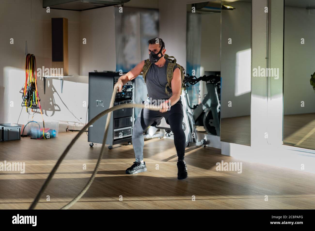 Sportif à l'entraînement de corde avec masque d'entraînement. Intérieur sur parquet en chêne avec soleil et ombre. Pour le concept de camp de démarrage. Banque D'Images