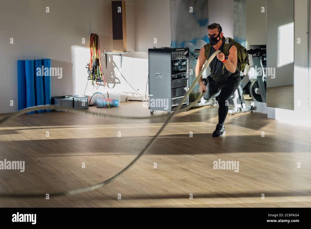 Sportif à l'entraînement de corde avec masque d'entraînement. Intérieur sur parquet en chêne avec soleil et ombre. Pour le concept de camp de démarrage. Banque D'Images