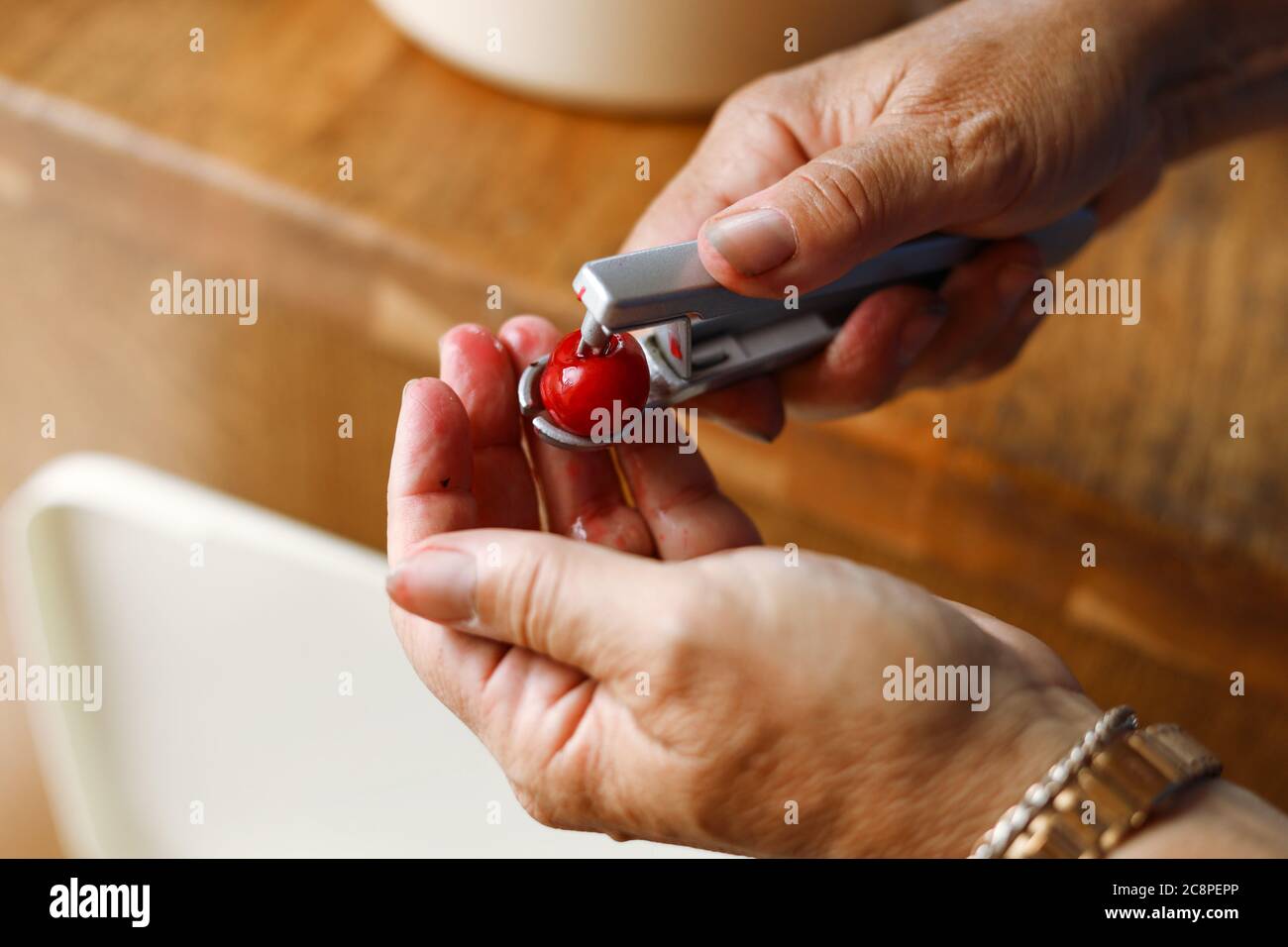 Les mains lapidation d'une cerise avec un cerisier Banque D'Images