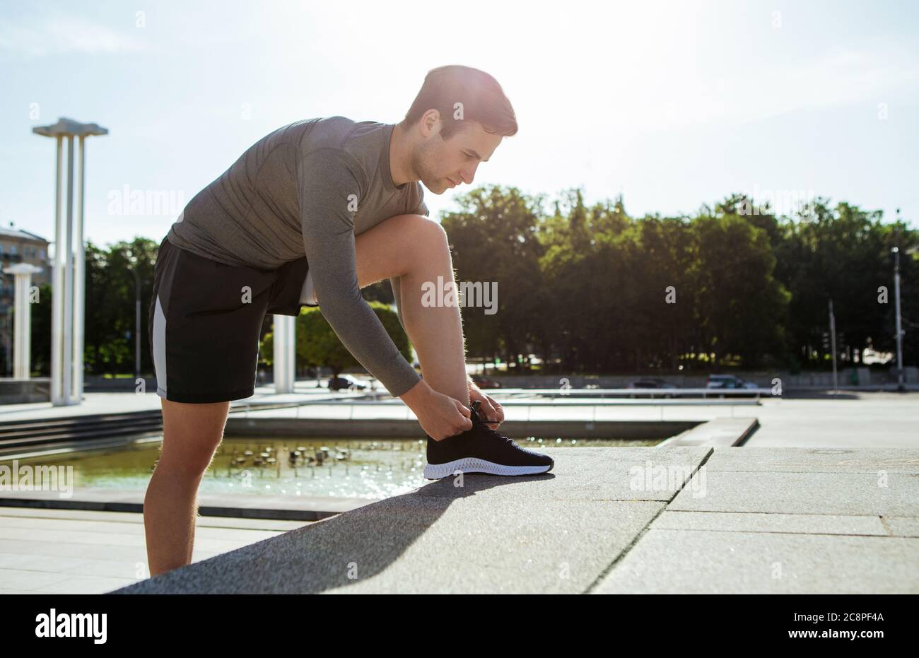 Début du marathon. Jeune homme beau nouant des lacets sur des marches Banque D'Images