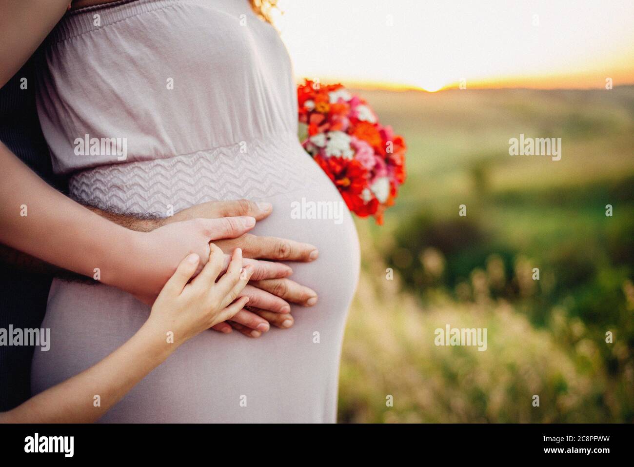 Mari et bébé mains sur le ventre de femme enceinte, prise de vue en extérieur, famille heureuse Banque D'Images