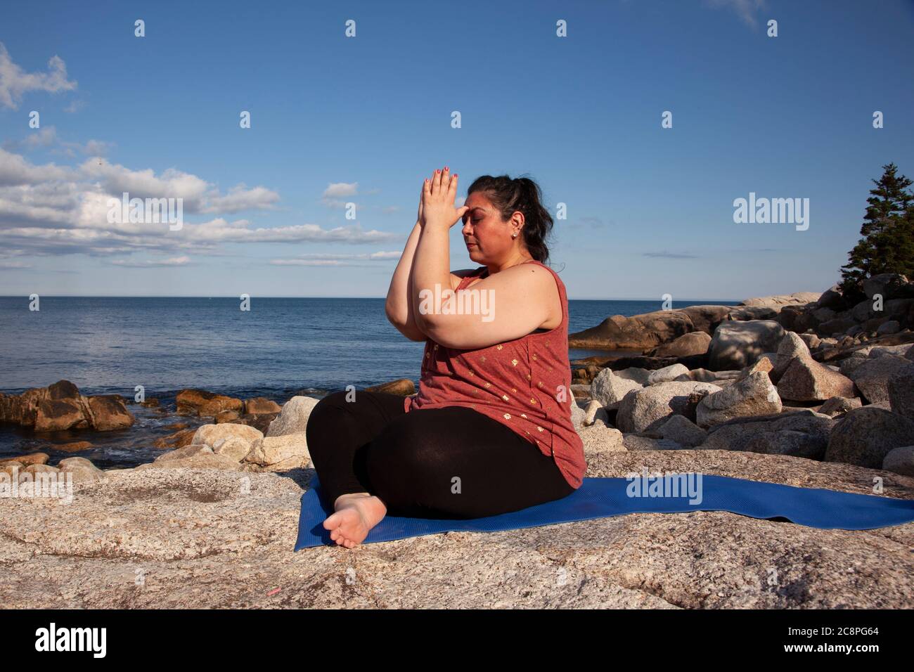 belle femme assise près de l'océan avec les mains au troisième œil pendant la méditation ou le yoga Banque D'Images