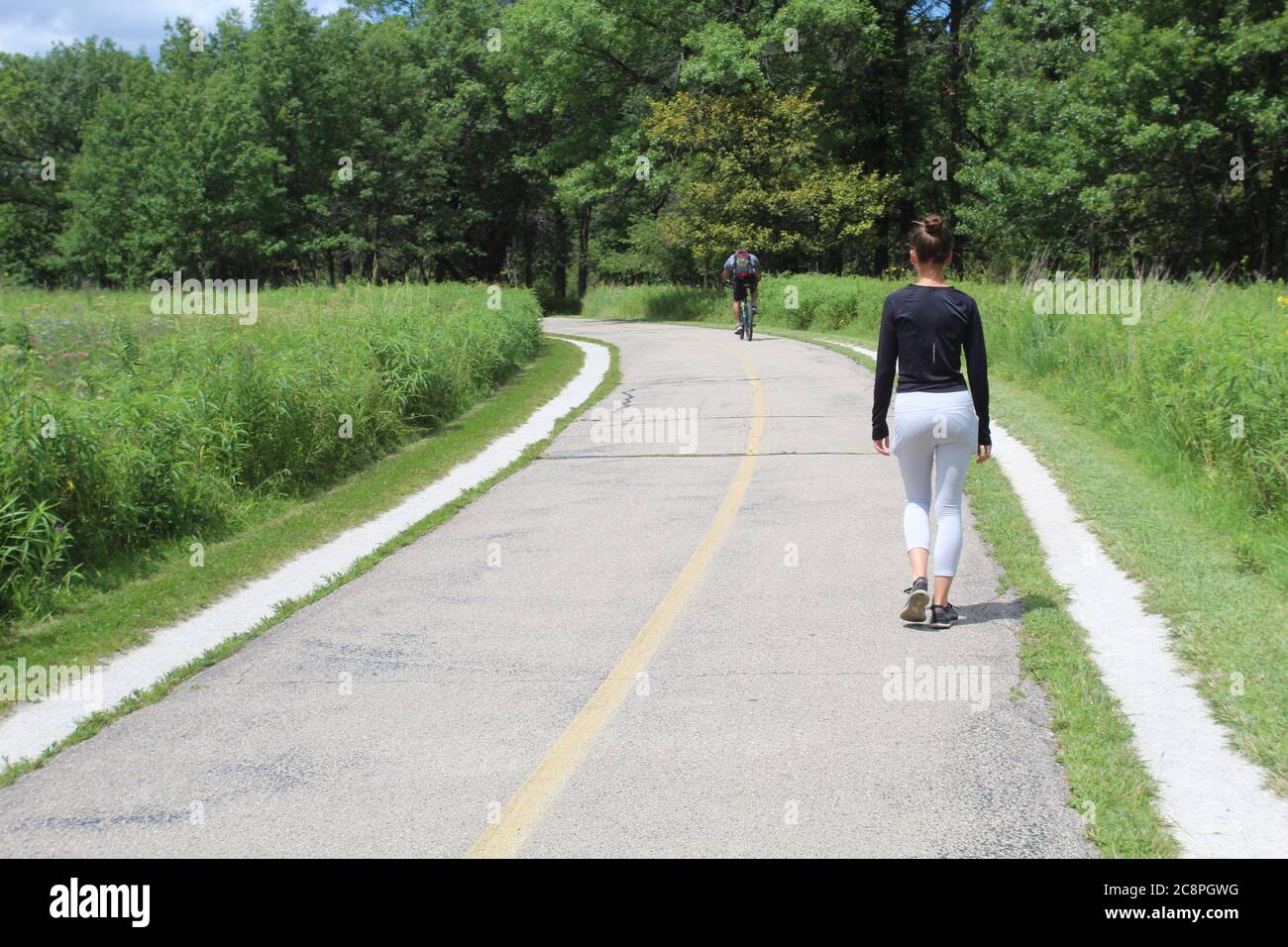 Femme marchant sur le sentier de la branche nord dans un pré avec un cycliste au loin à Miami Woods à Morton Grove, Illinois Banque D'Images