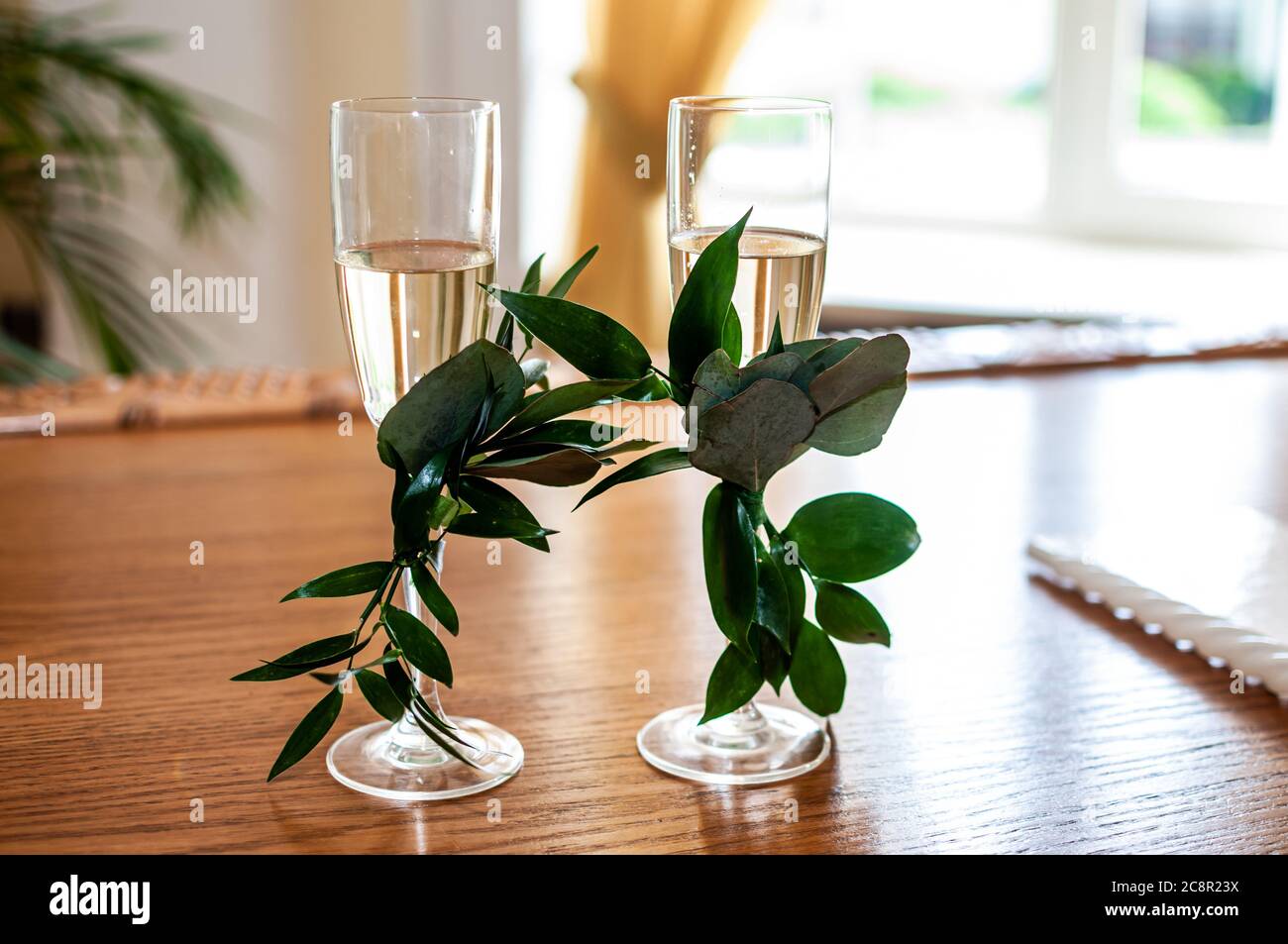 des verres de champagne sont décorés de branches vertes sur la table Banque D'Images