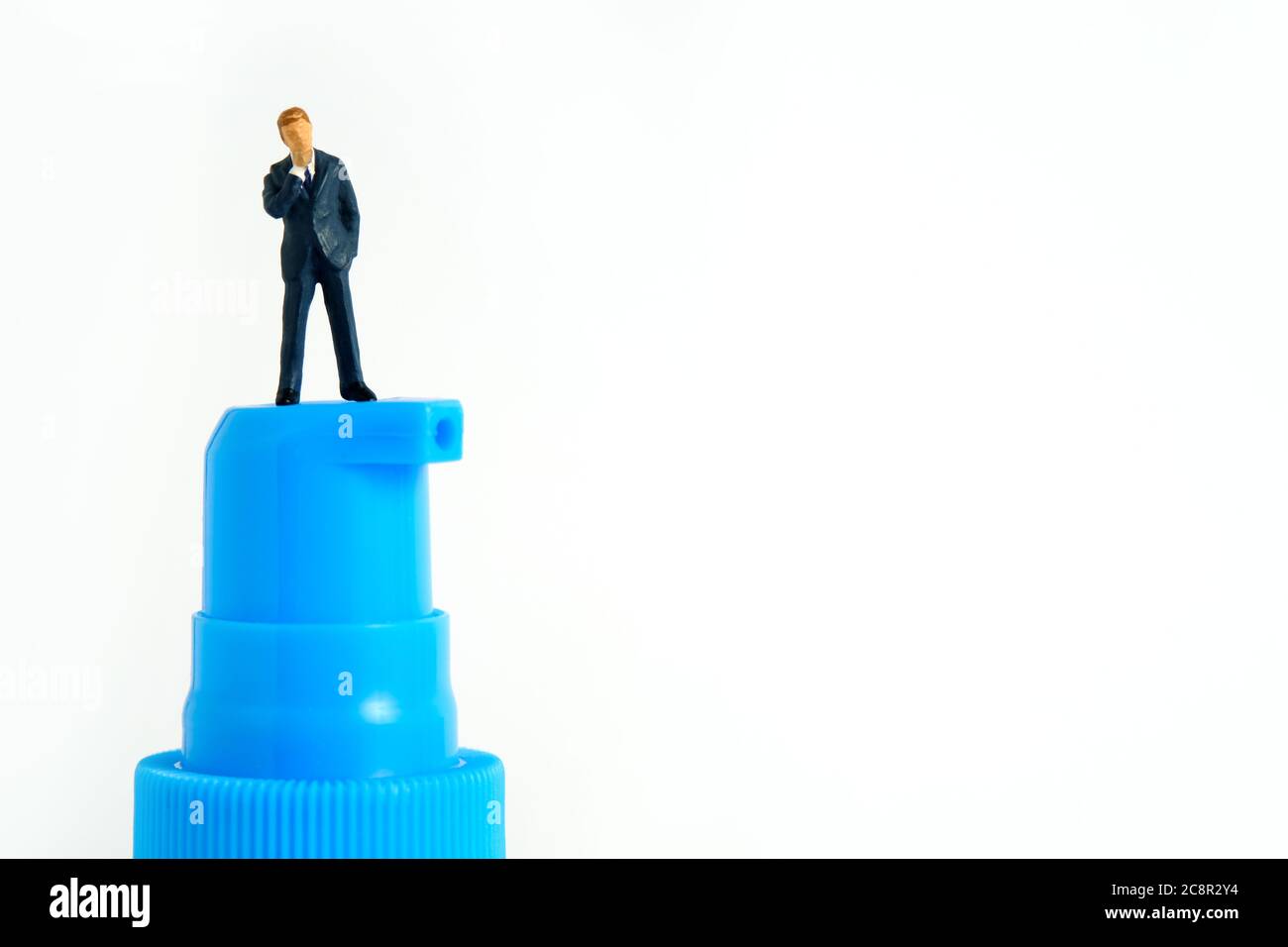 Photo miniature conceptuelle de la santé – un homme d'affaires se tient au-dessus d'une bouteille de désinfectant pour les mains. Image Banque D'Images
