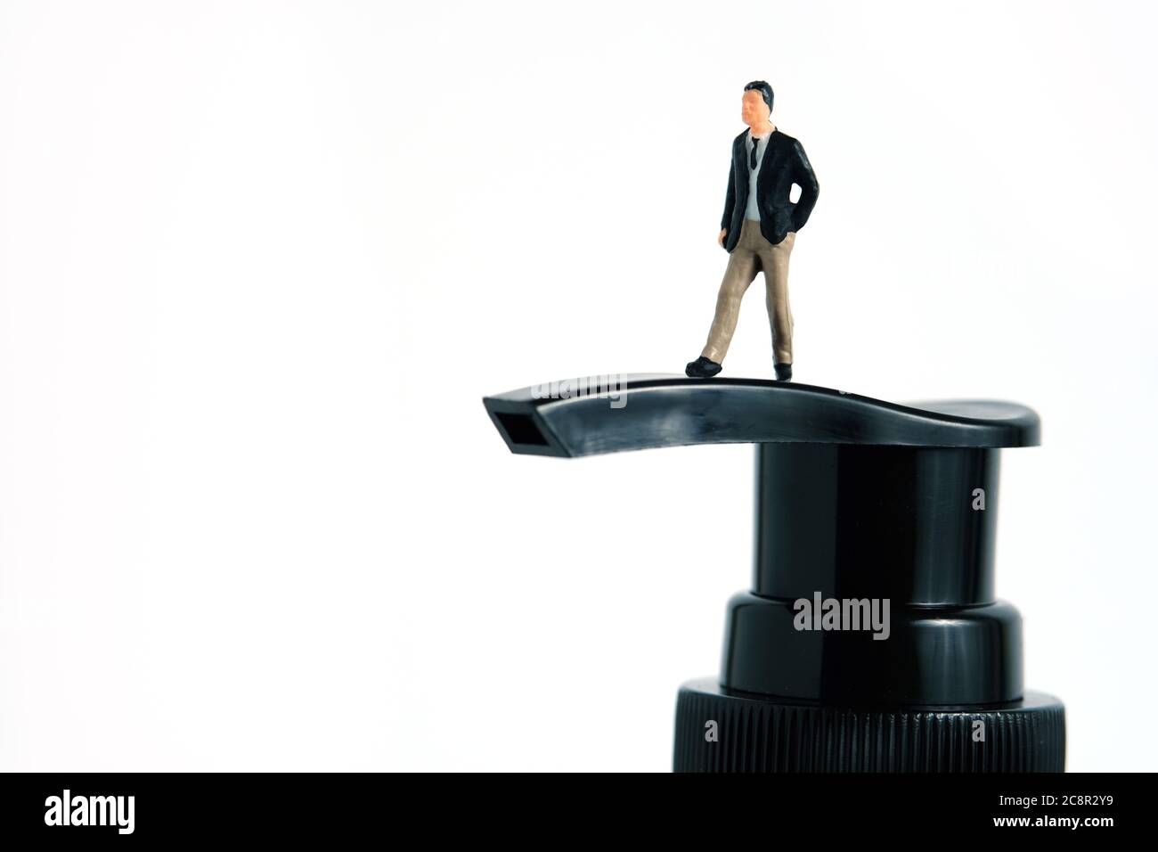 Photo miniature conceptuelle de la santé – un homme d'affaires se tient au-dessus d'une bouteille de désinfectant pour les mains. Image Banque D'Images