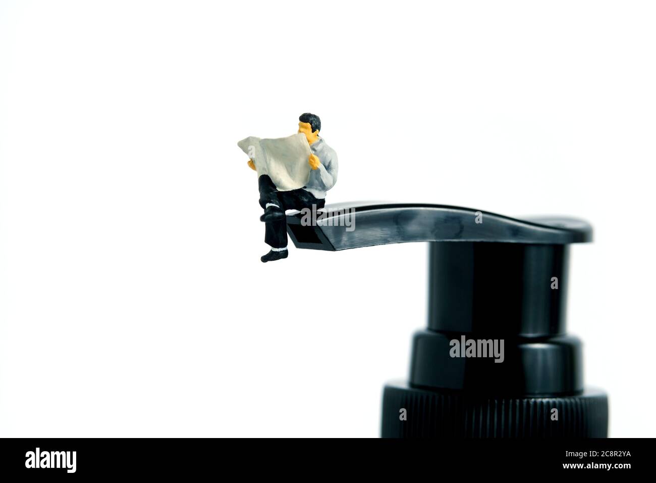 Photographie conceptuelle de la santé – personnes miniatures lisant au-dessus d'un flacon de désinfectant pour les mains – lisez comment appliquer un désinfectant pour protéger du virus. Image Pho Banque D'Images
