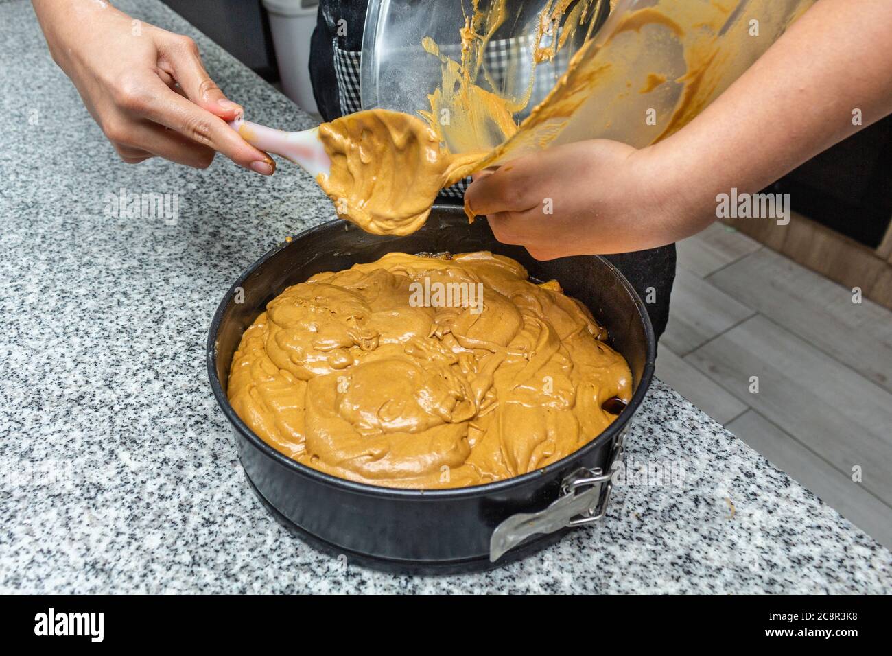 Mains versant le gâteau fini dans le moule Banque D'Images