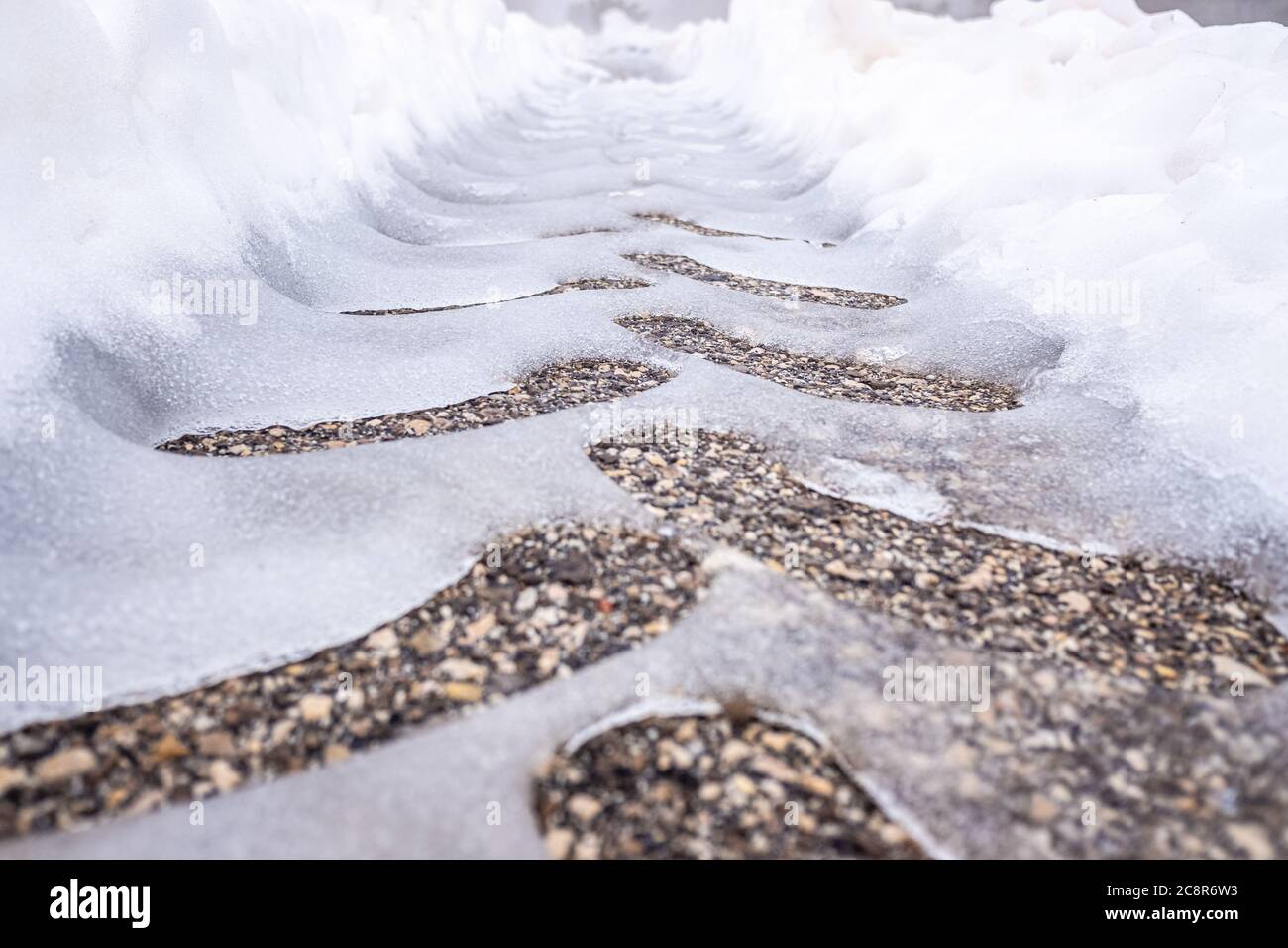 Traces d'un pneu de tracteur sur de l'asphalte neigeux sur une route en hiver. Banque D'Images