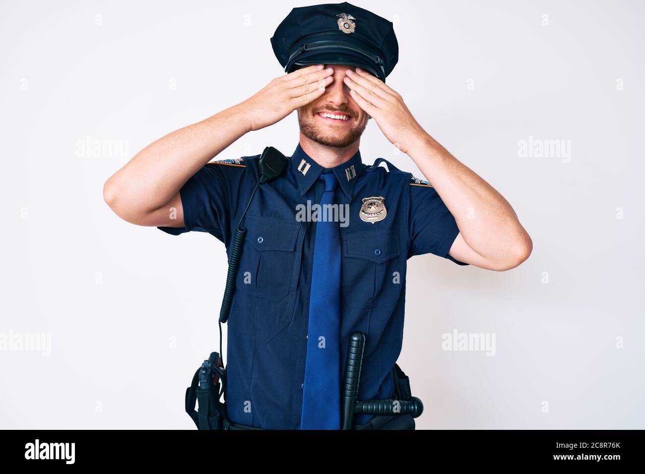 Jeune homme de race blanche portant l'uniforme de police couvrant les yeux  avec les mains souriantes et drôles. Concept aveugle Photo Stock - Alamy